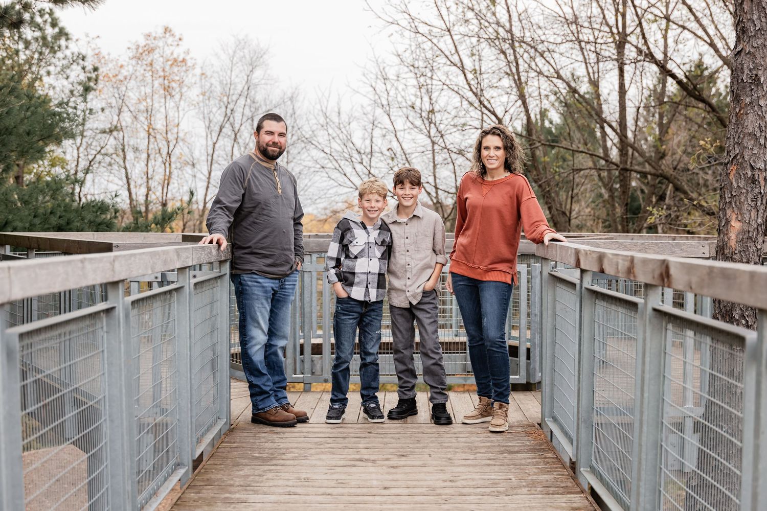 Shada family stands in the middle of a bridge walkway with the bare trees behind them