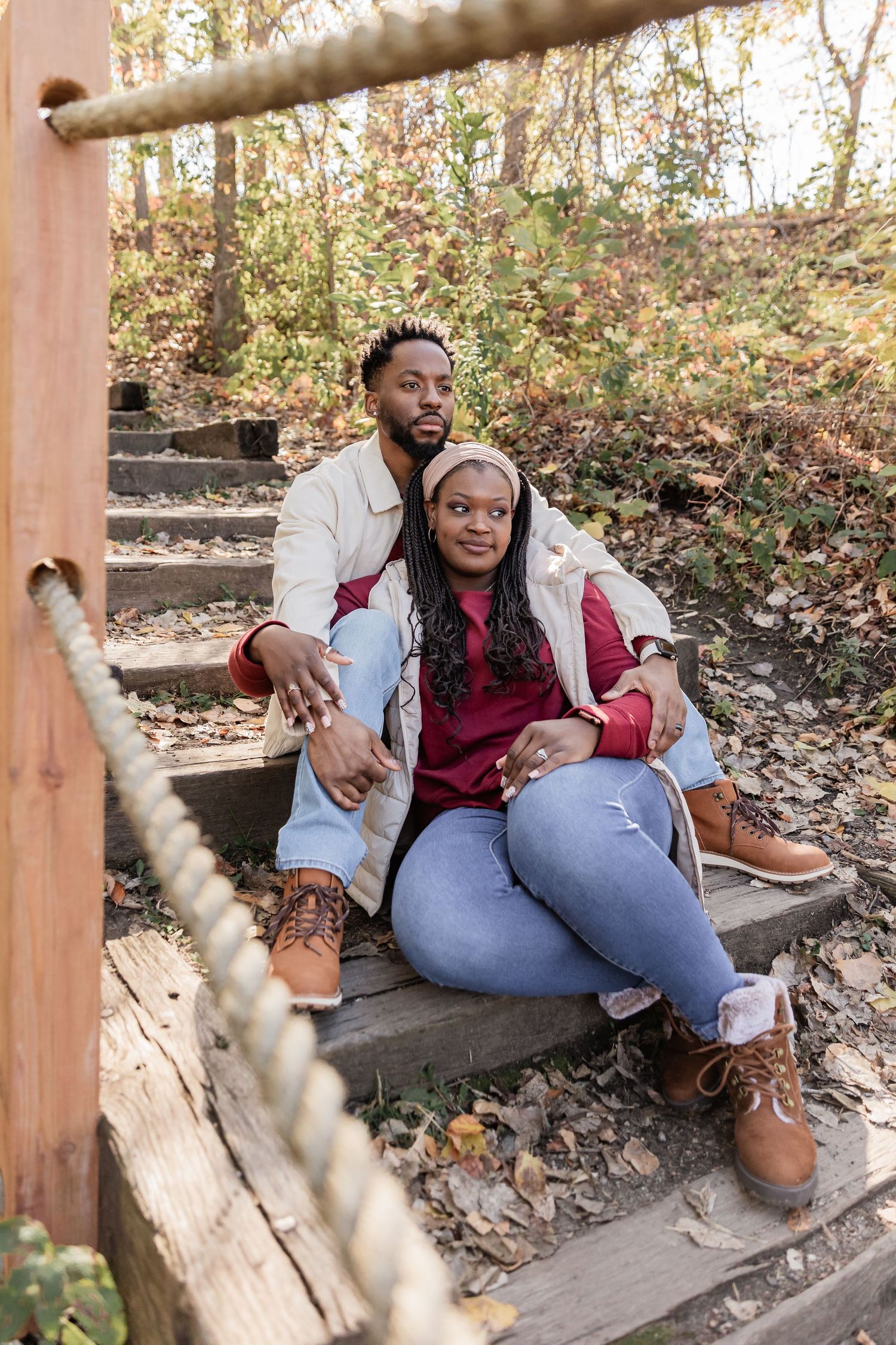 Young African American couple sits on a dirt covered staircase as they stare off into the distance
