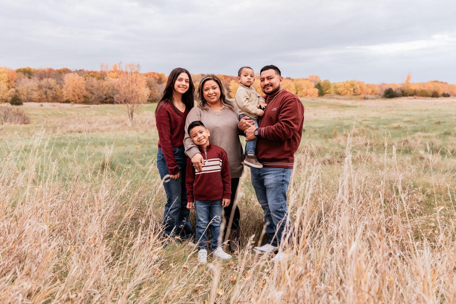 Archila family has a big group hug in front of a red and golden forest