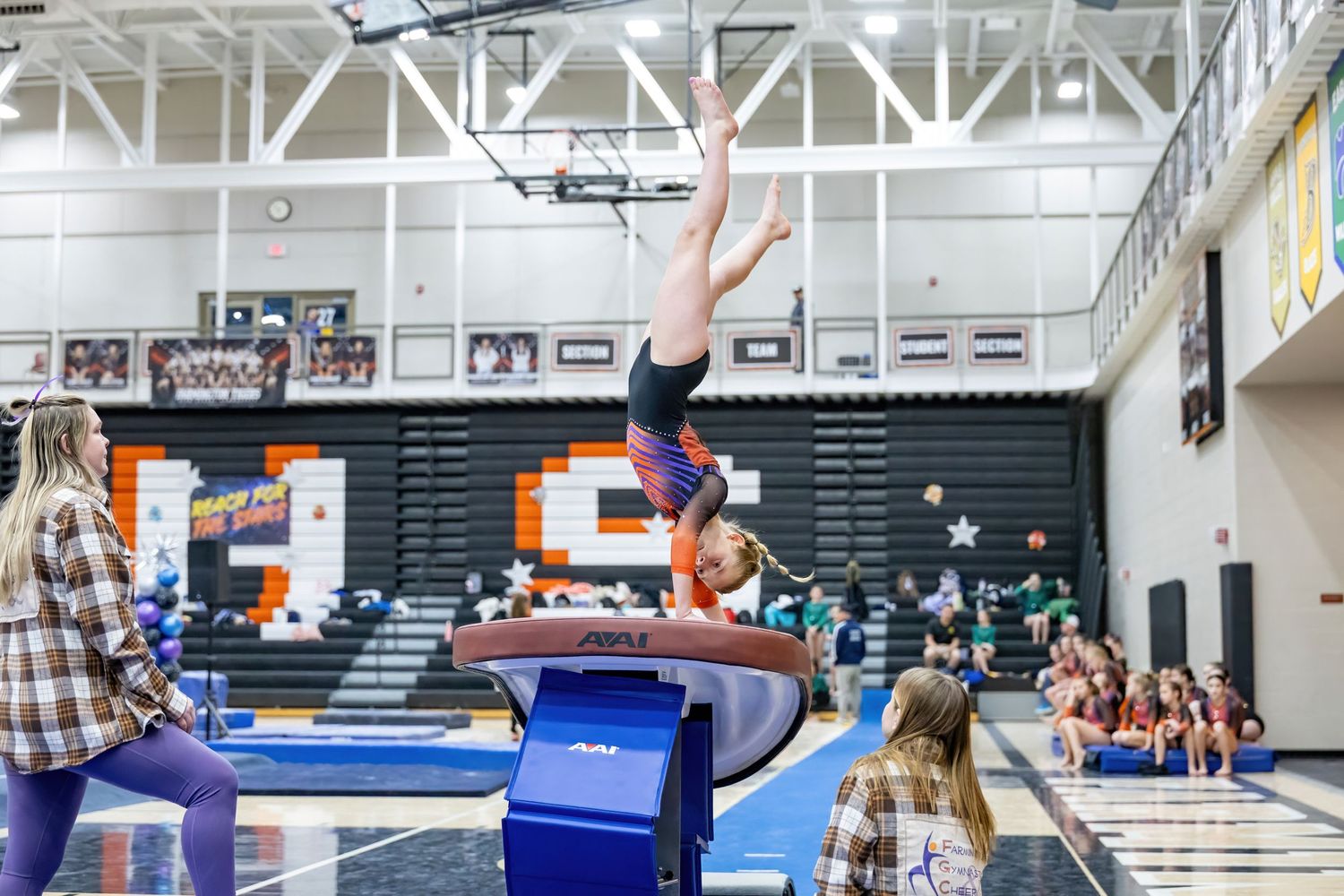 Farmington Gymnastics and Cheer athlete flips over the vault and flips to the landing below