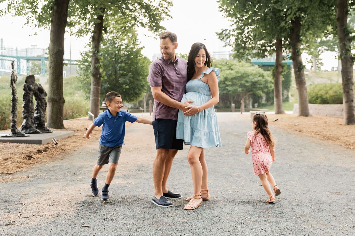 Pregnant wife and her husband watch as their kids run circles around them at Minneapolis Sculpture Garden