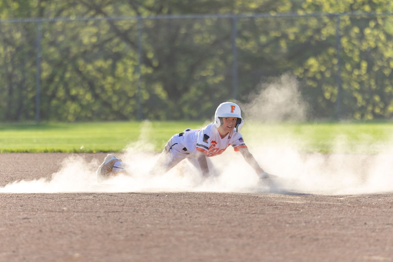 Youth baseball player slides into second base after stealing the base