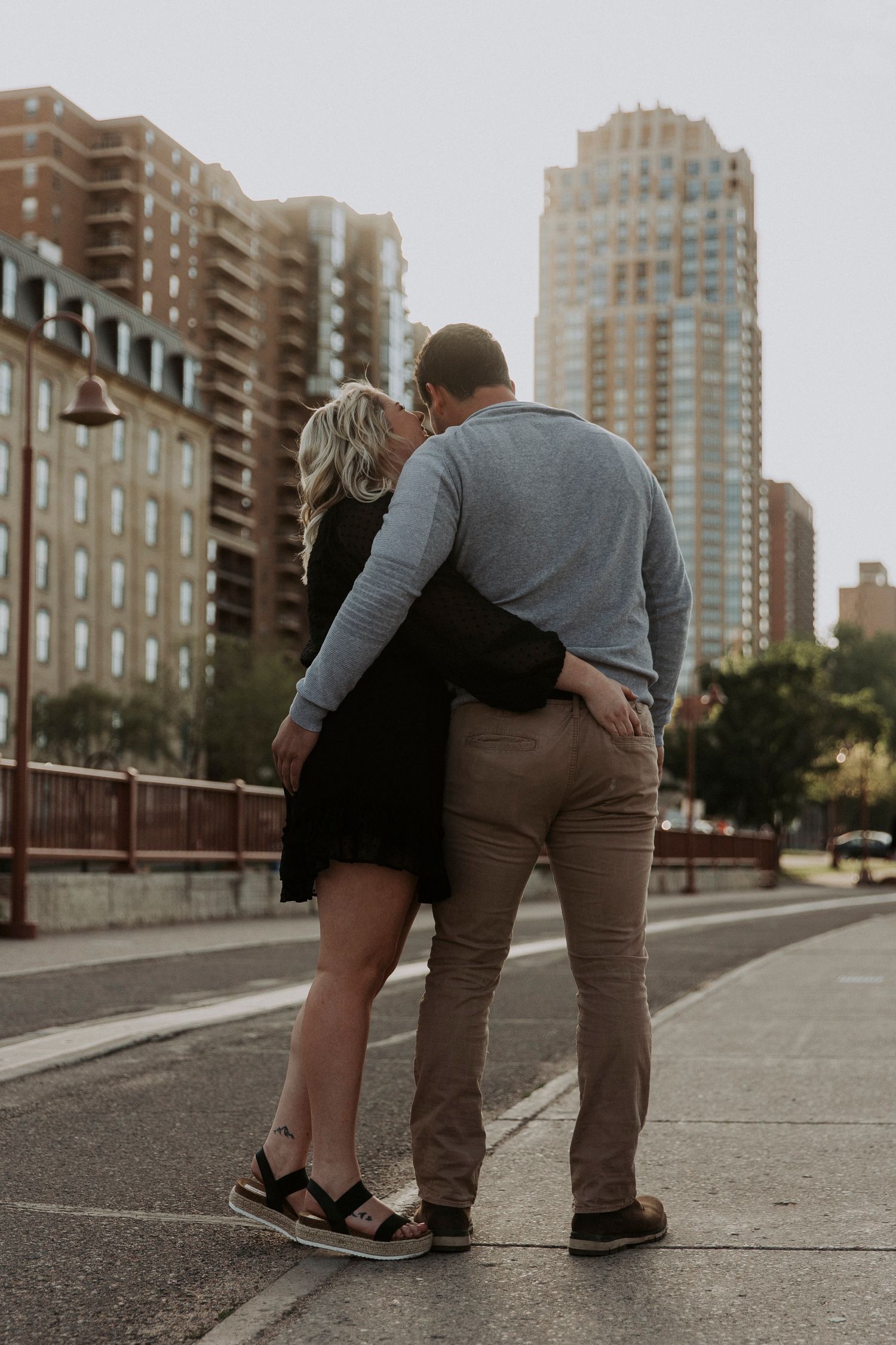 young couple pinch each other's butts on stone arch bridge