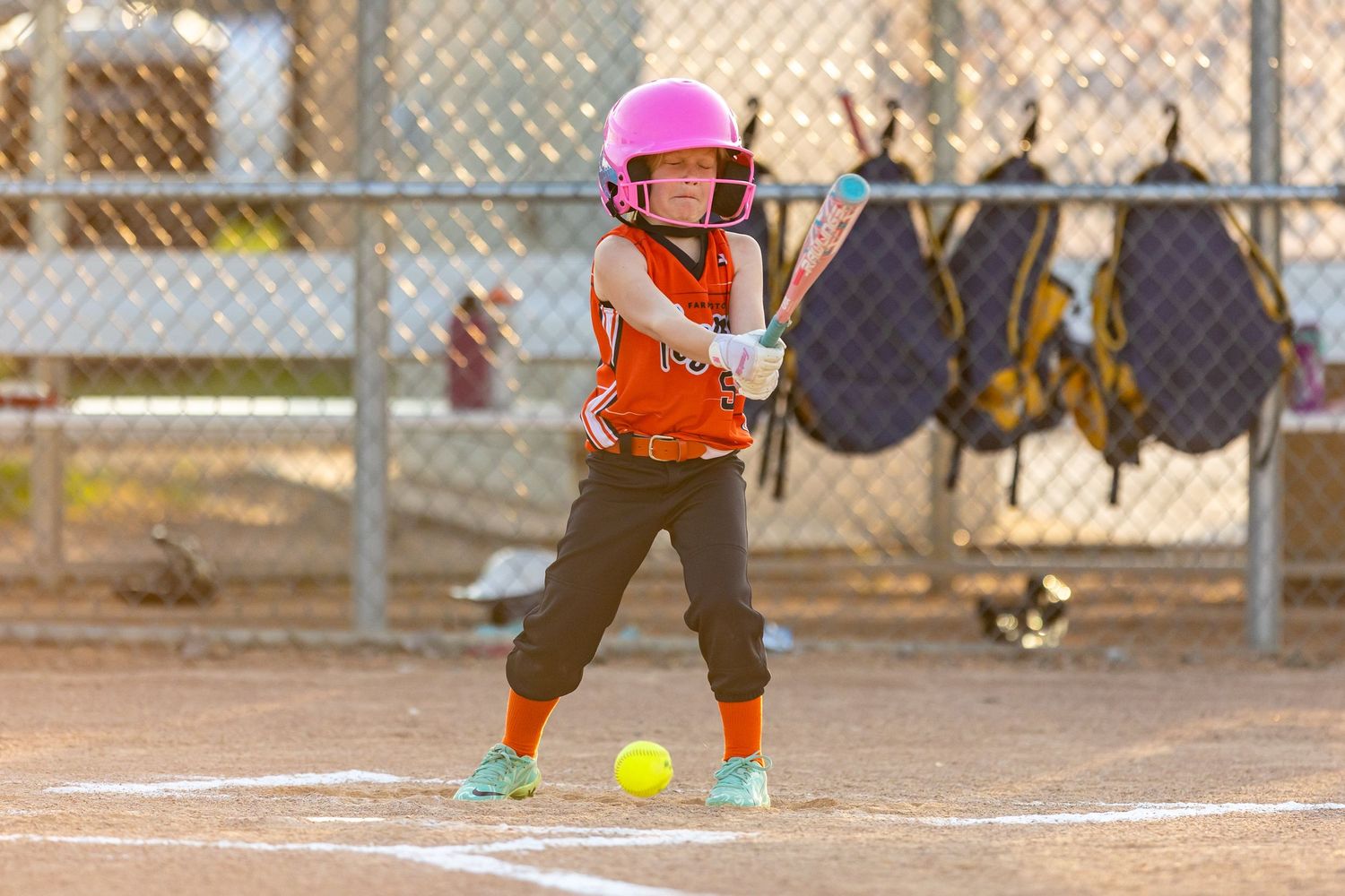 Youth softball player hits a short grounder towards the pitcher