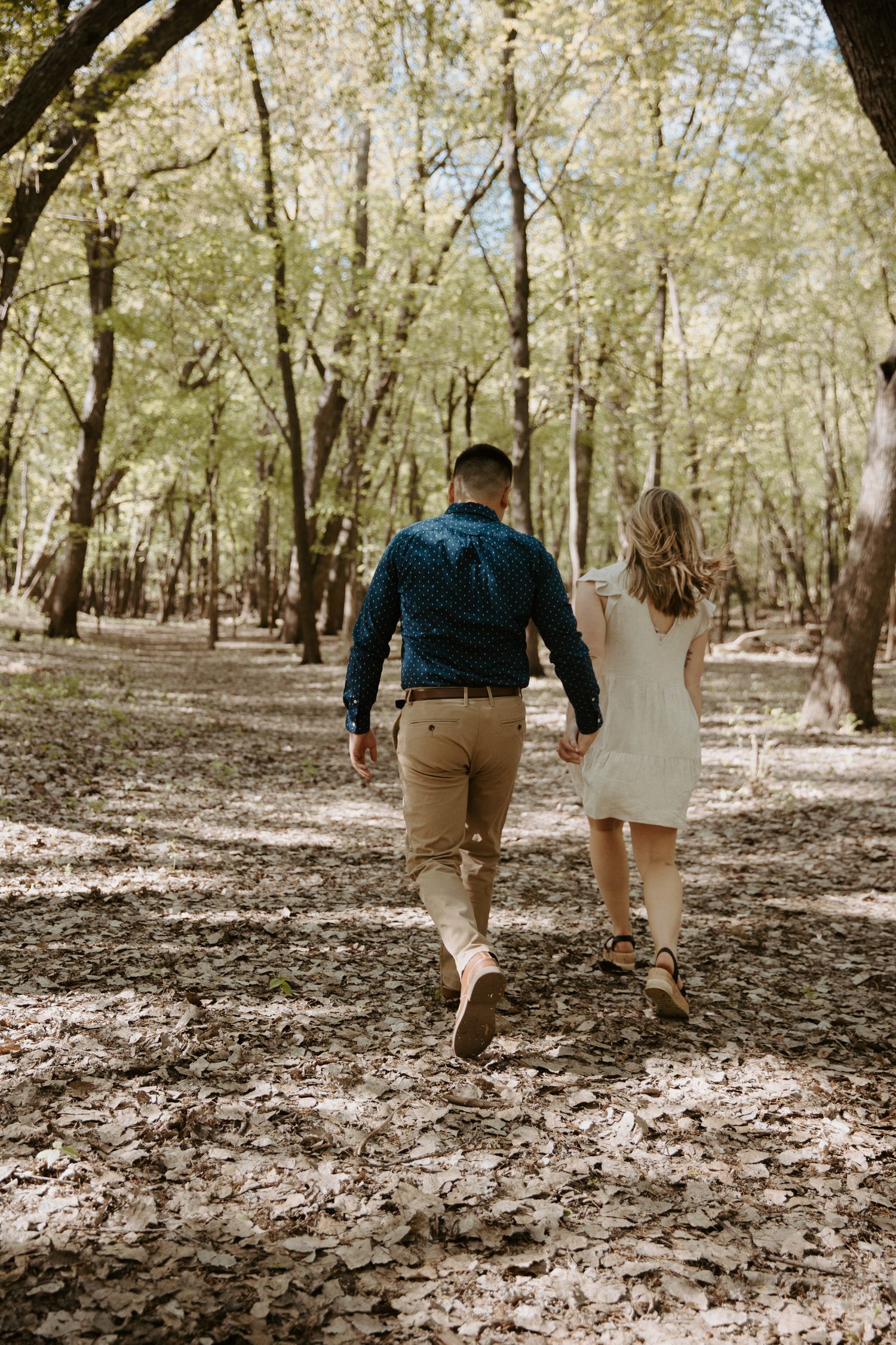 Young couple walk hand in hand away from the camera as they stare at each other
