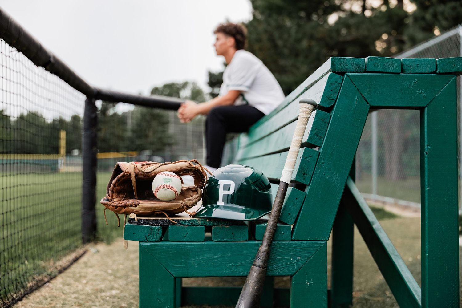 Dominic Staves sits on a bench staring out at the field from the dugout