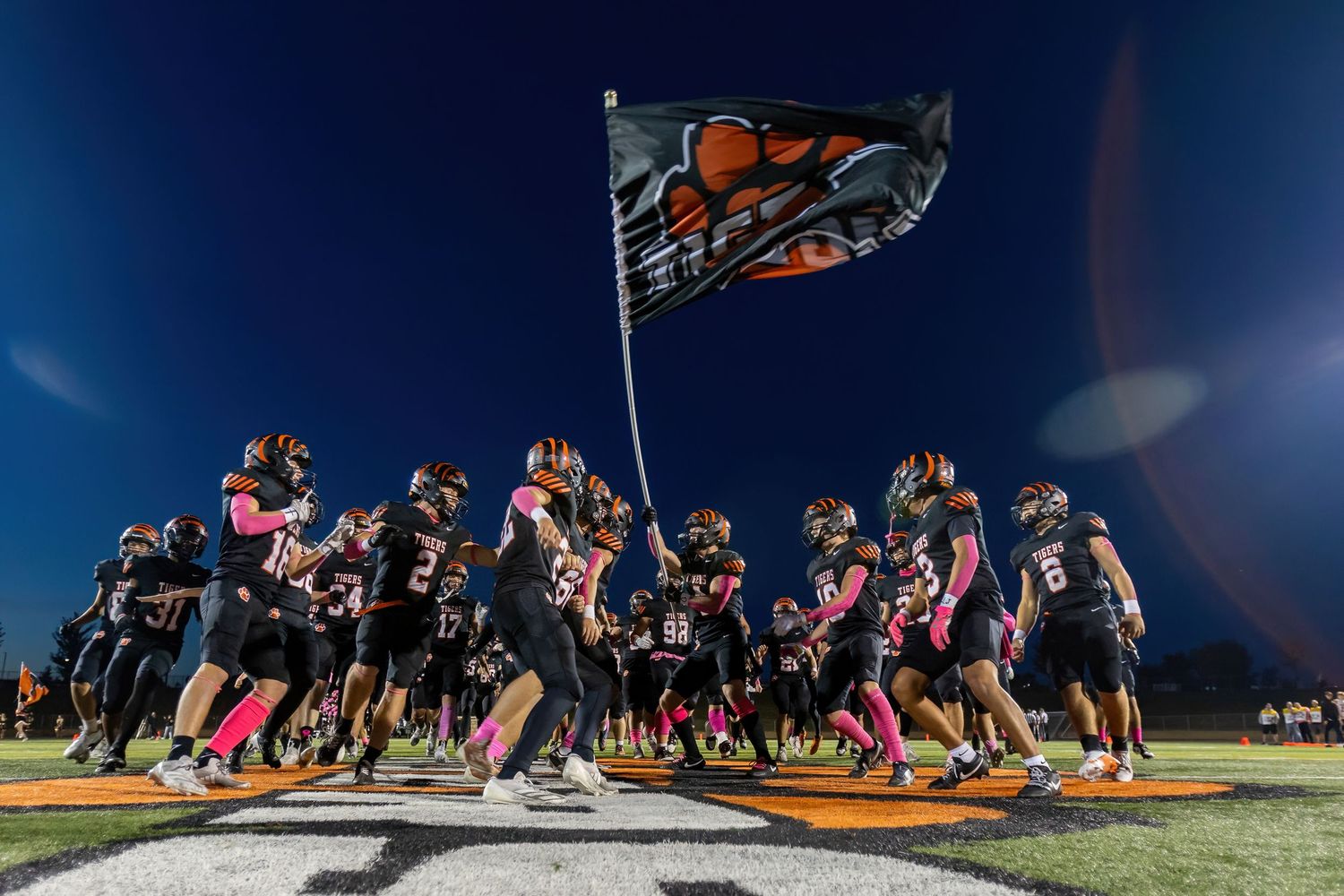 Farmington Tigers football team comes together at center field to hoist the team flag before their game