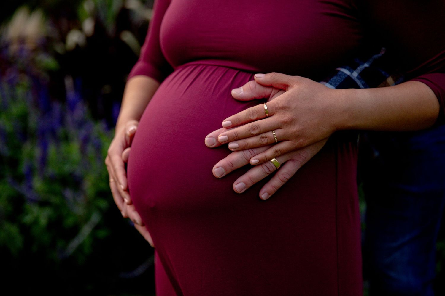 young couple embrace wife's baby bump