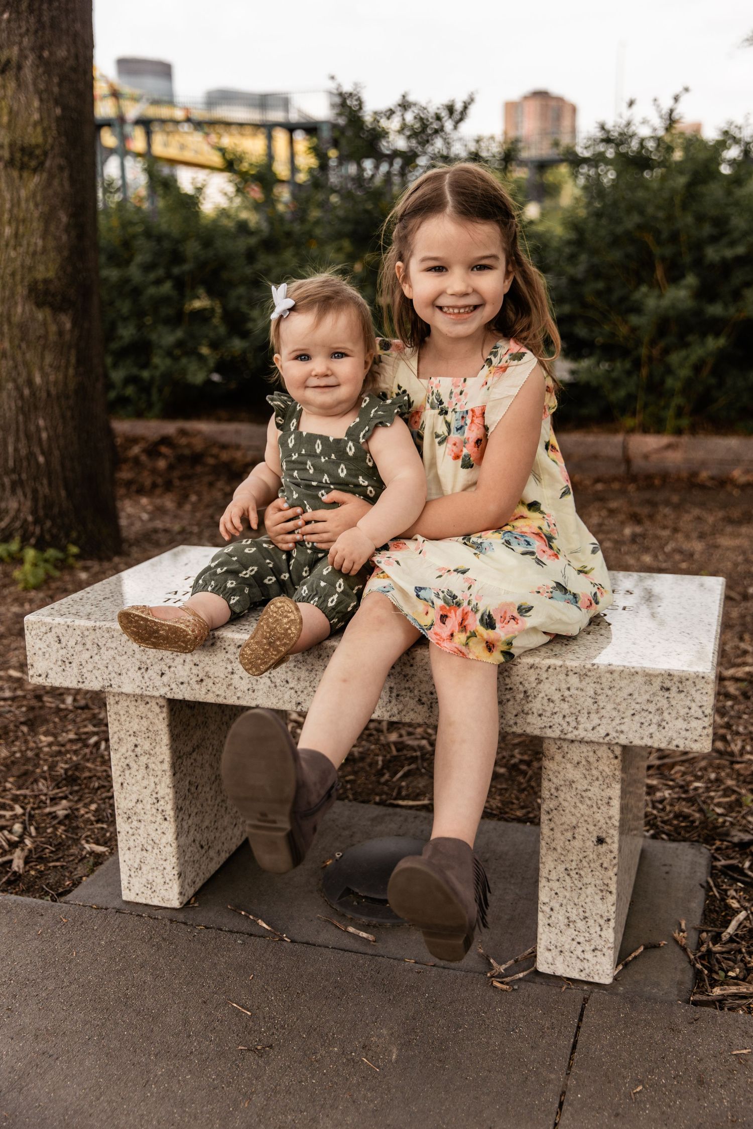 Young girl sitting on a small marble bench with her little sister