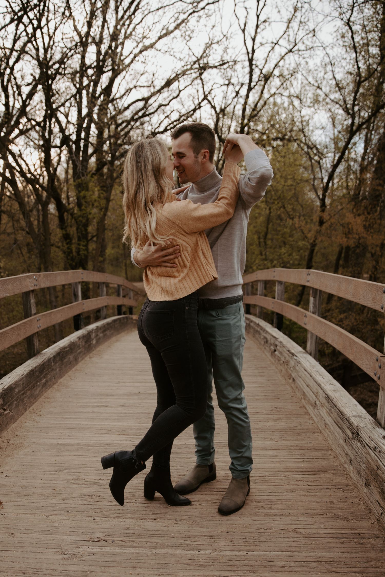 Young couple dance with each other on an old wooden bridge over a creek