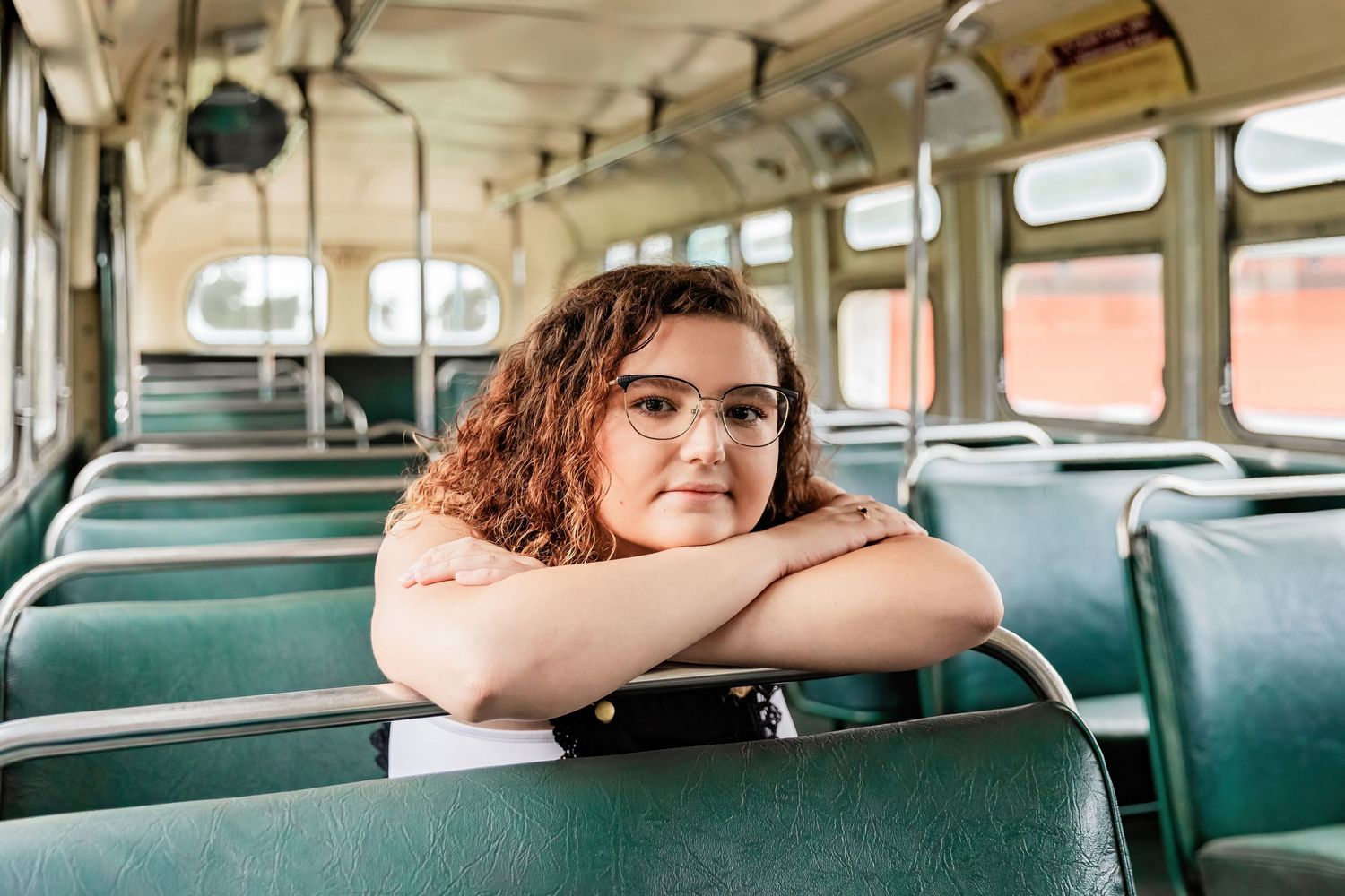 Savannah leans over the seat of an old commuter bus at Little Log Cabin in Hastings