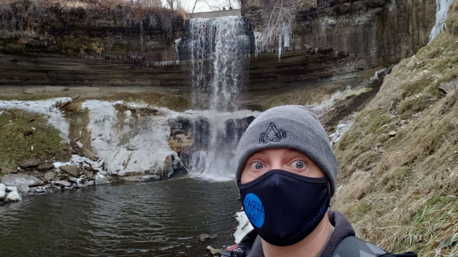 masked photographer at frozen waterfall