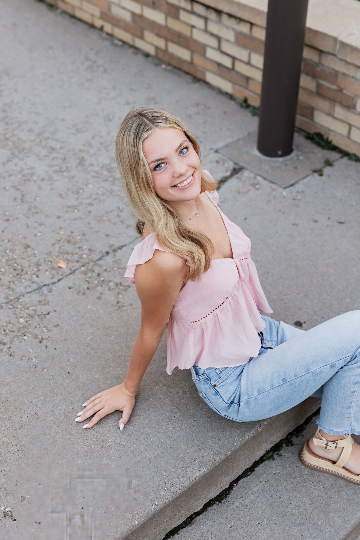 Lucy leans back on her palms sitting atop a small staircase as she gives a glowing smile up to the camera