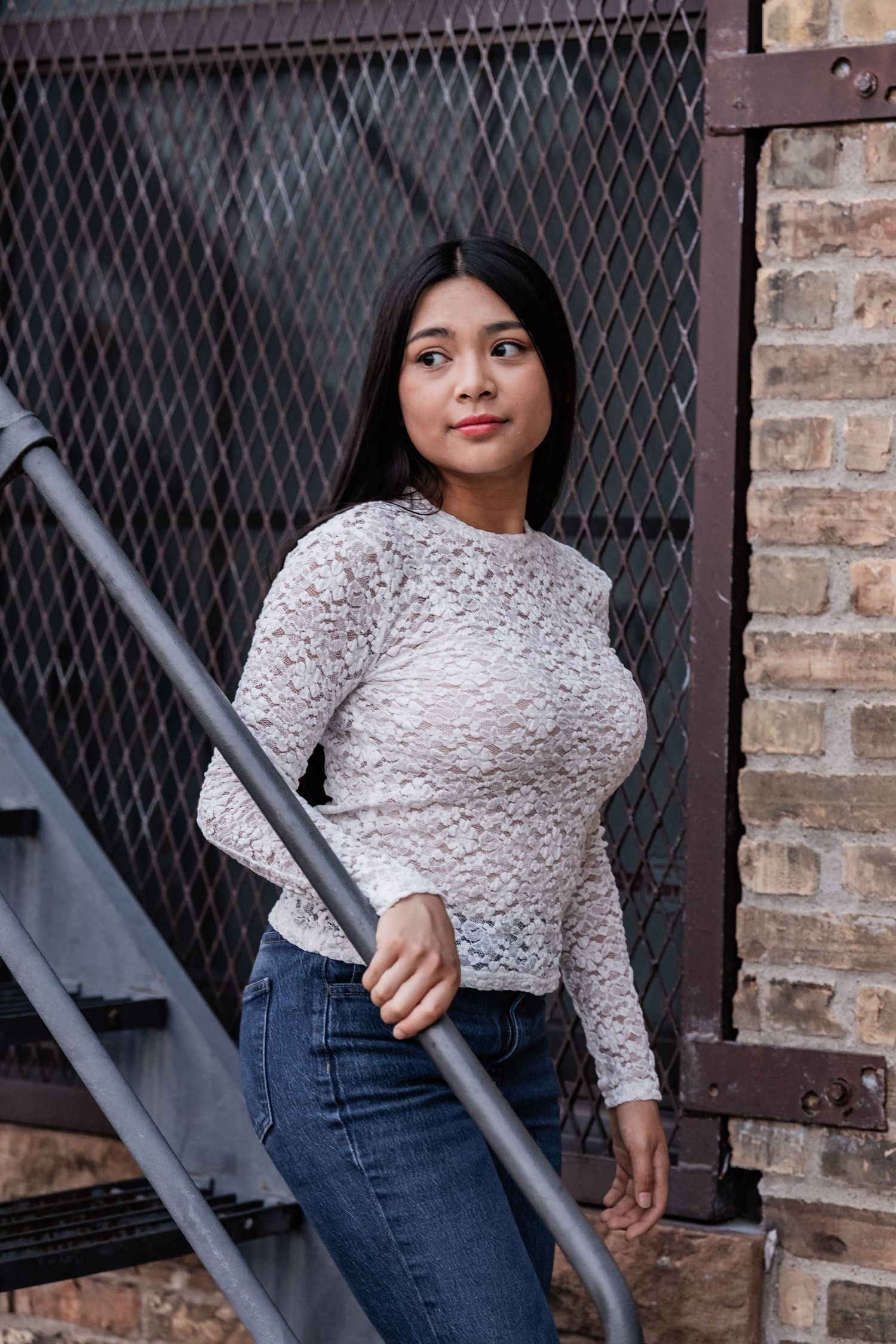 Nina walks down a metal staircase as the glances over her shoulder off into the distance