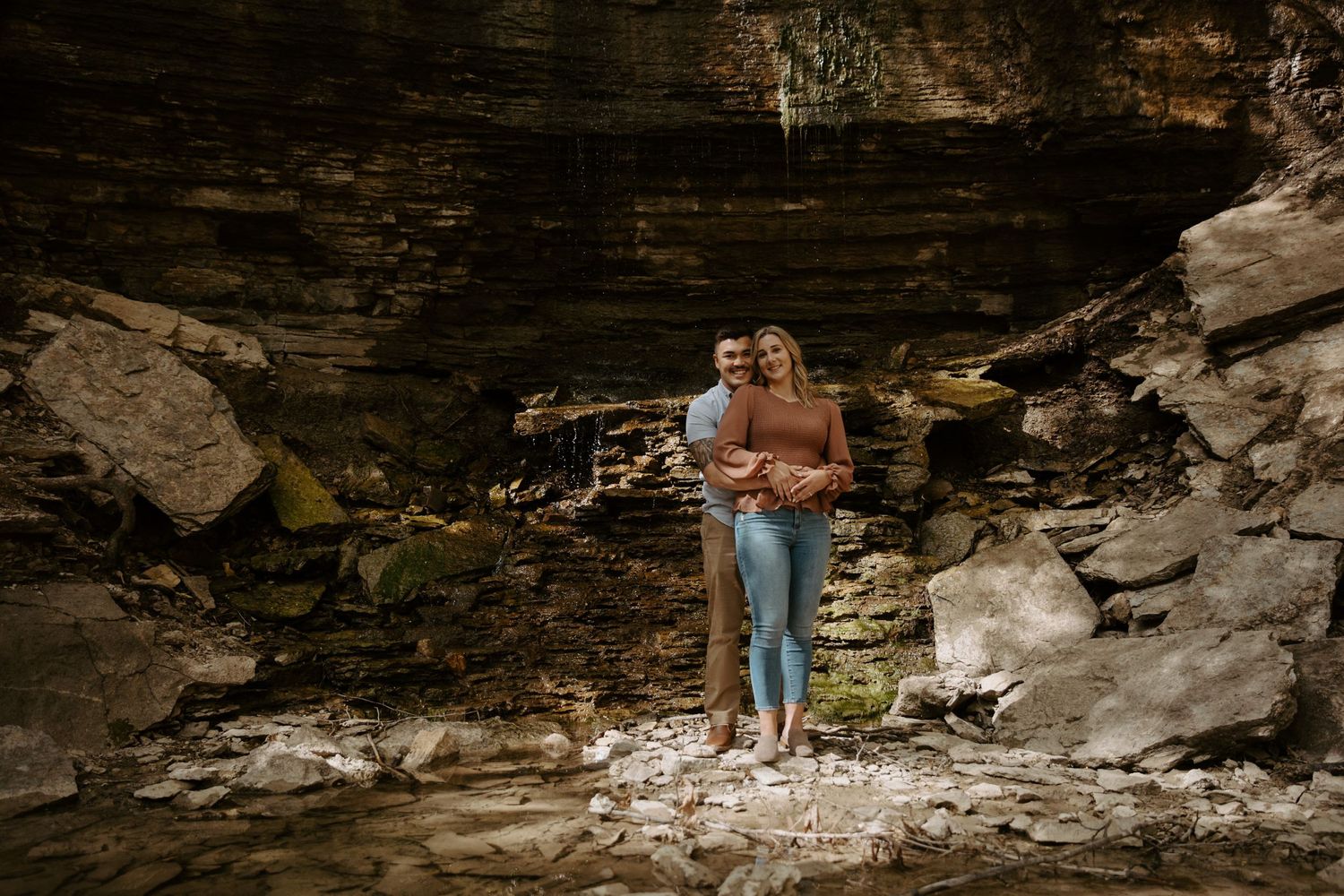 young engaged couple embrace each other in a rock bed