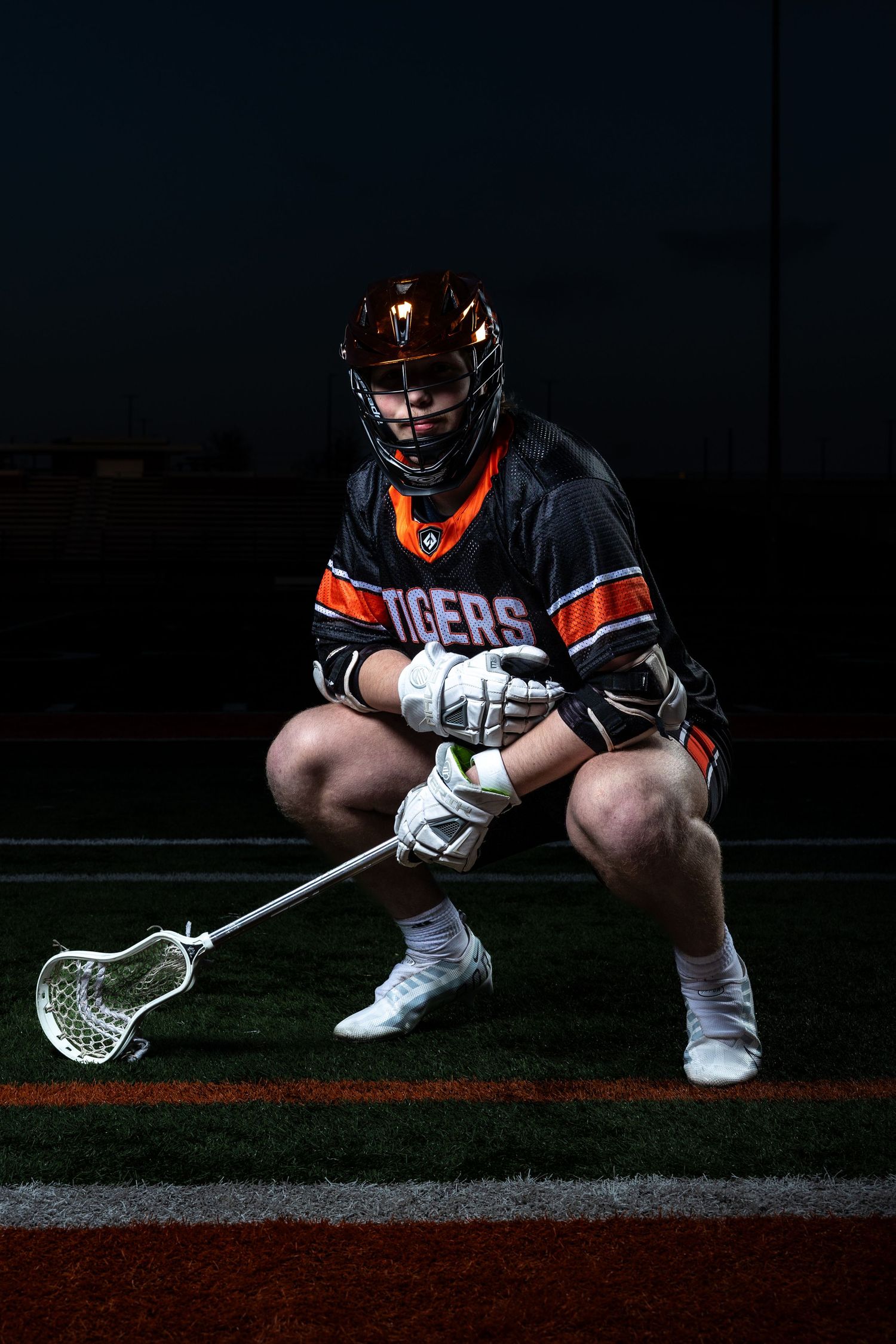 Farmington Tigers boys lacrosse player crouches down as he stares down the camera for media day