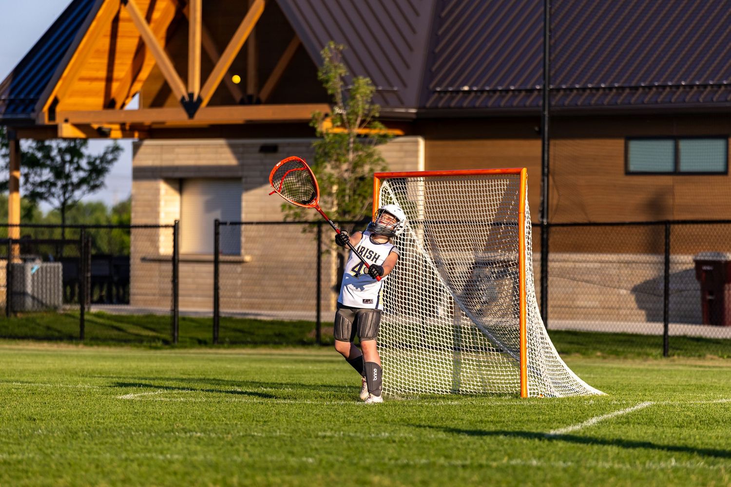 Girls youth lacrosse goalies passes the ball up the field to her teammate