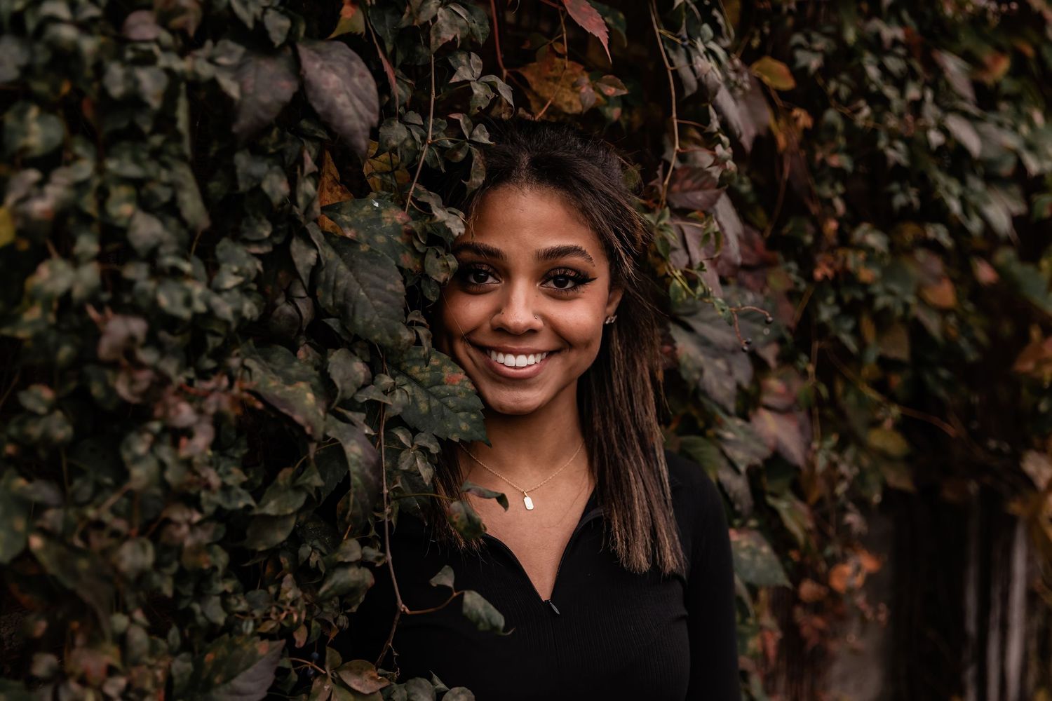 Young teenage girl leans into an ivy covered wall in downtown Stillwater for her senior photos