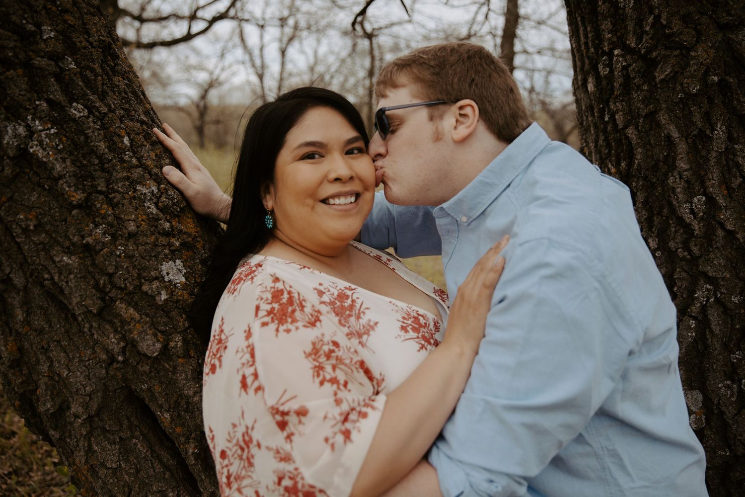 Man leans in to kiss his fiance on the cheek