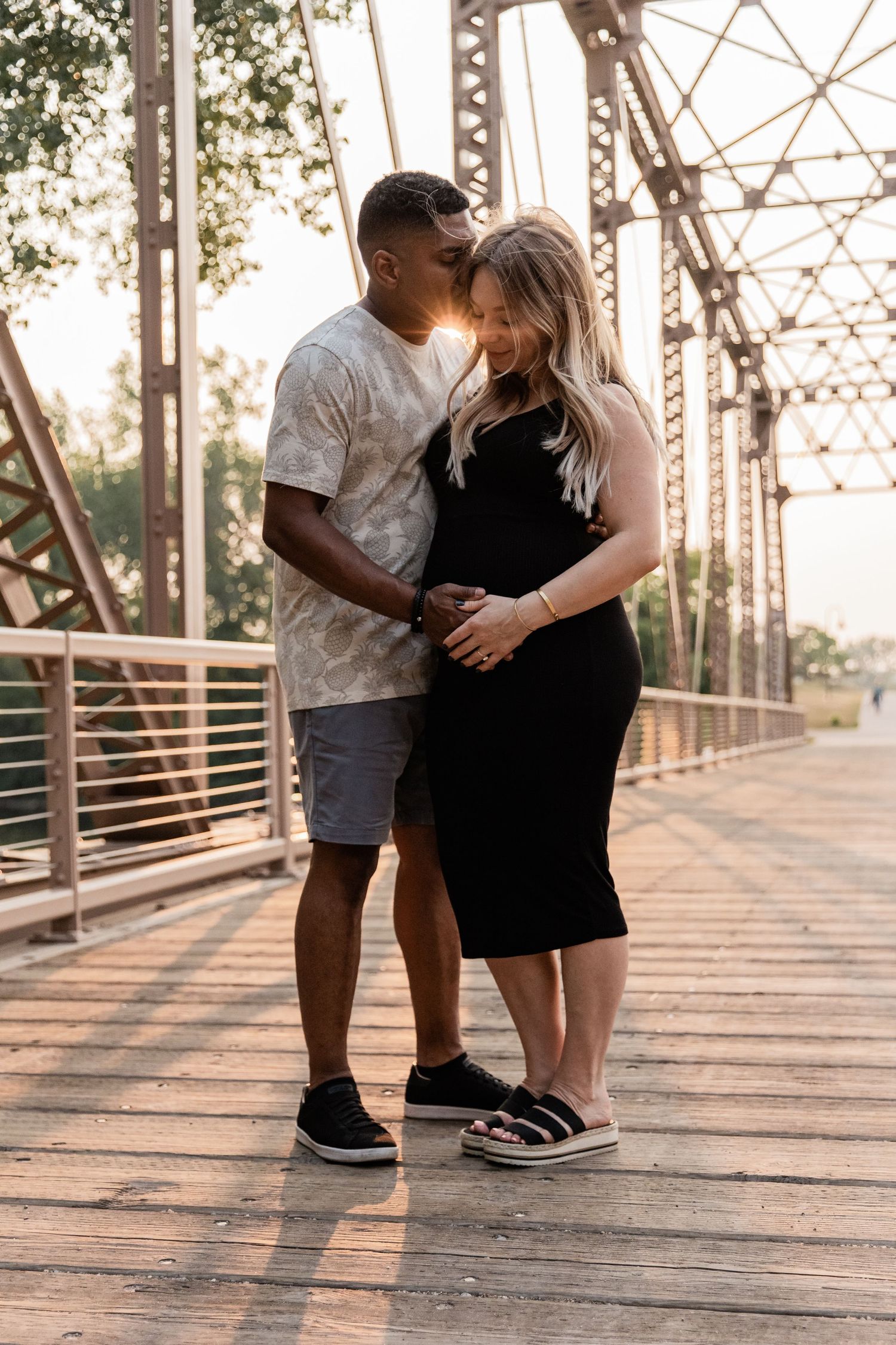 Man holds his pregnant wife close as they both hold the baby bump