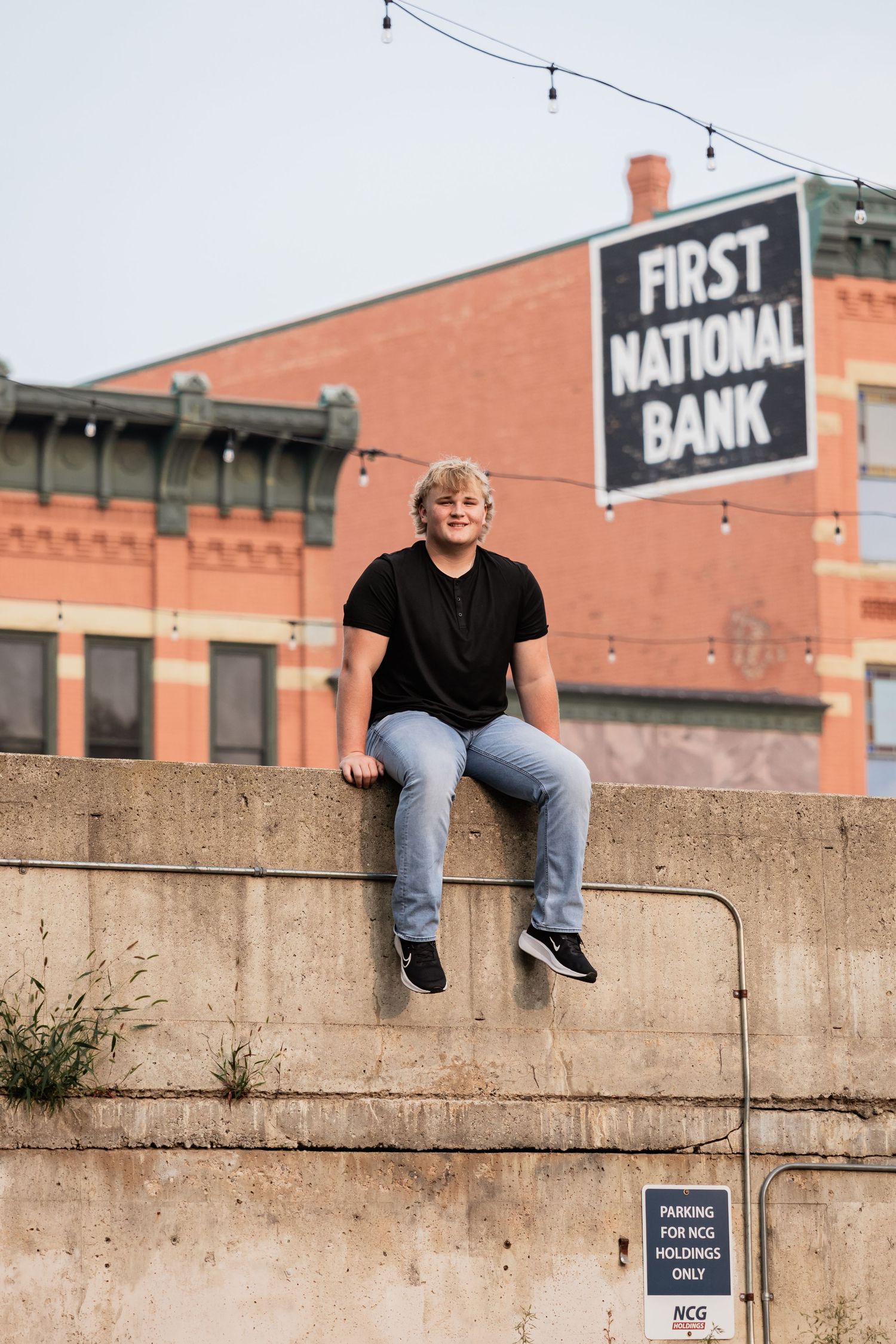 Isaac rests on an elevated ledge in a parking lot as the buildings surround him