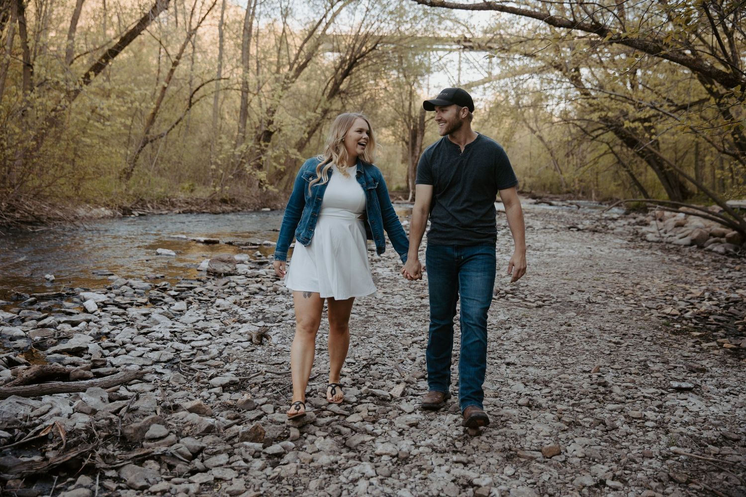 young engaged couple strolls along a flowing river bed