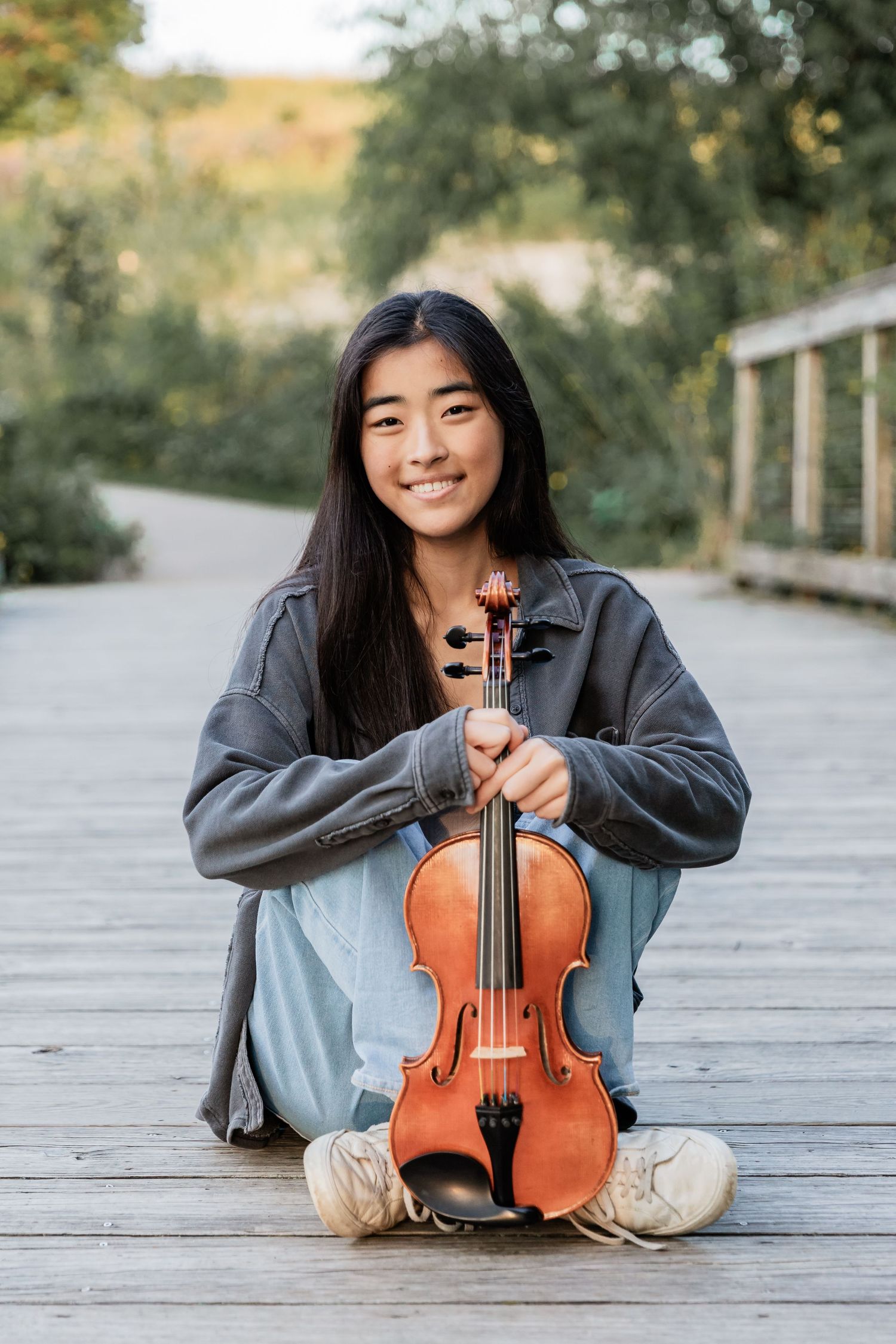 Maya holds her violin in front of her as she poses for her senior photos at Lebanon Hills Park in Eagan