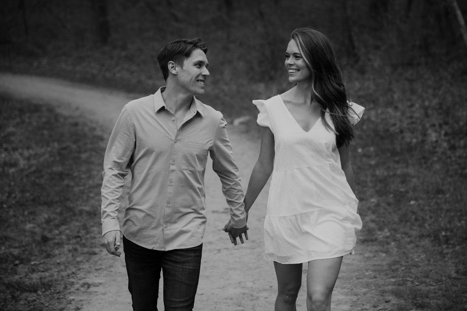 young engaged couple strolls hand in hand down path