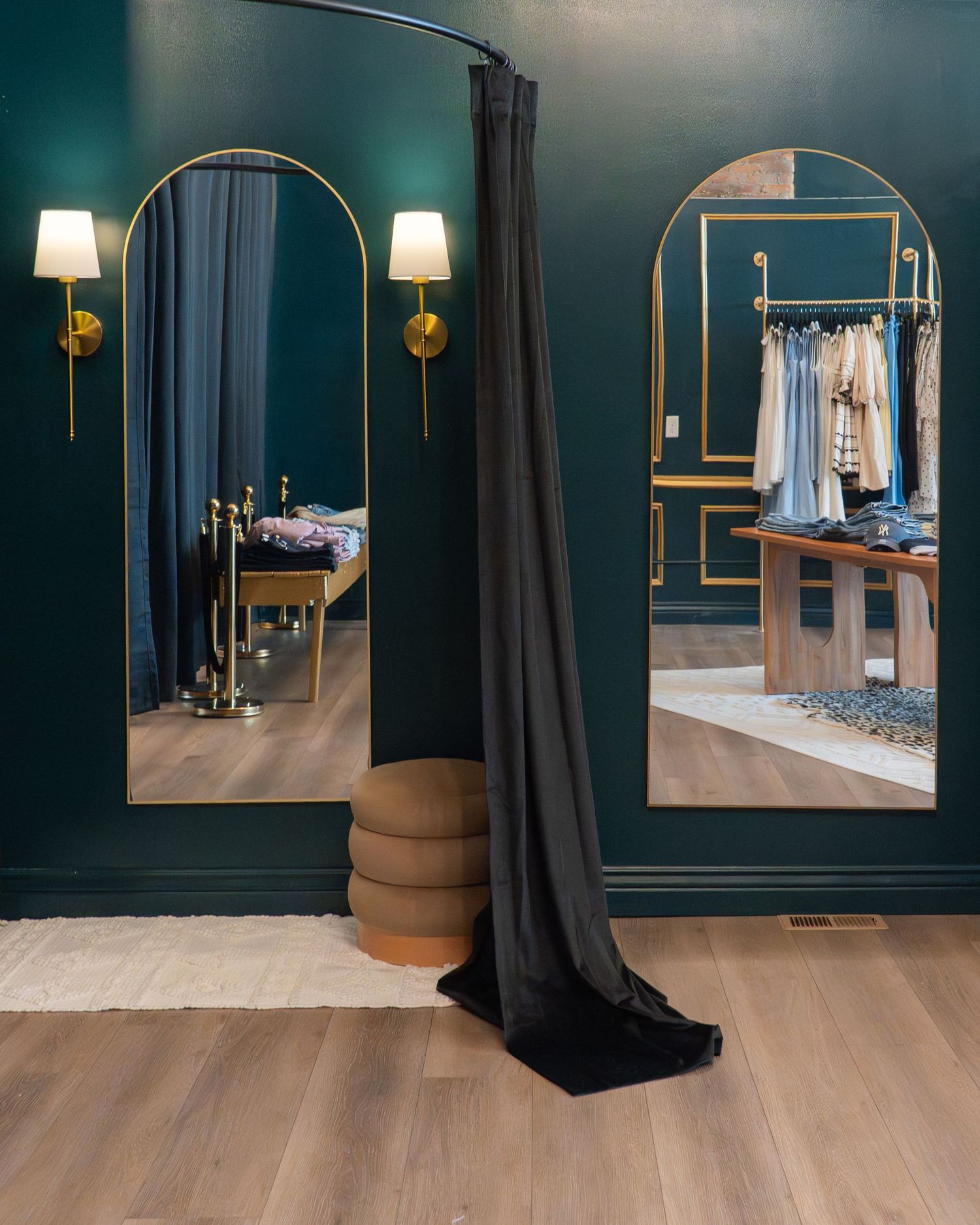 A sleek clothing boutique interior featuring dark teal walls, hardwood floors, and minimalist clothing displays.