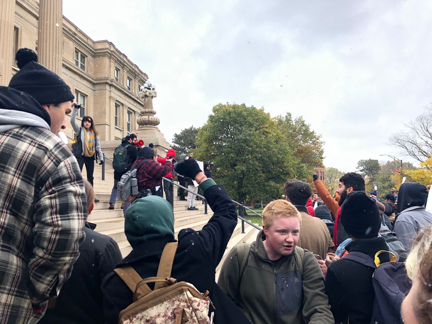 A large crowd of protesters gathered outside a stone building.