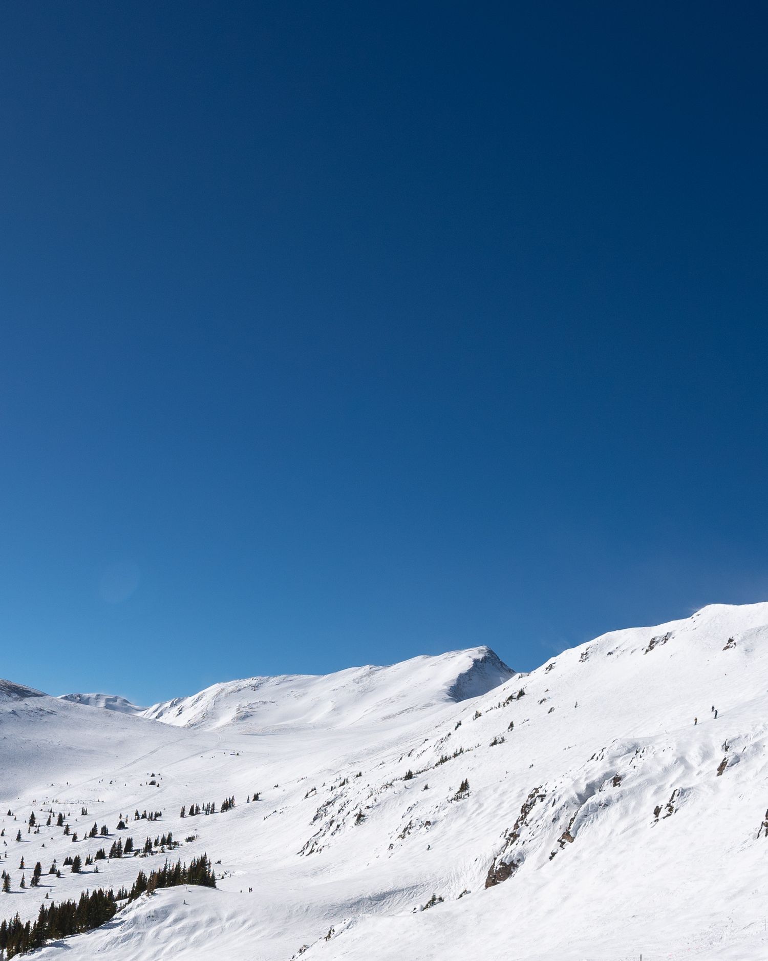Pristine snow-covered mountain slopes against deep blue sky in winter.