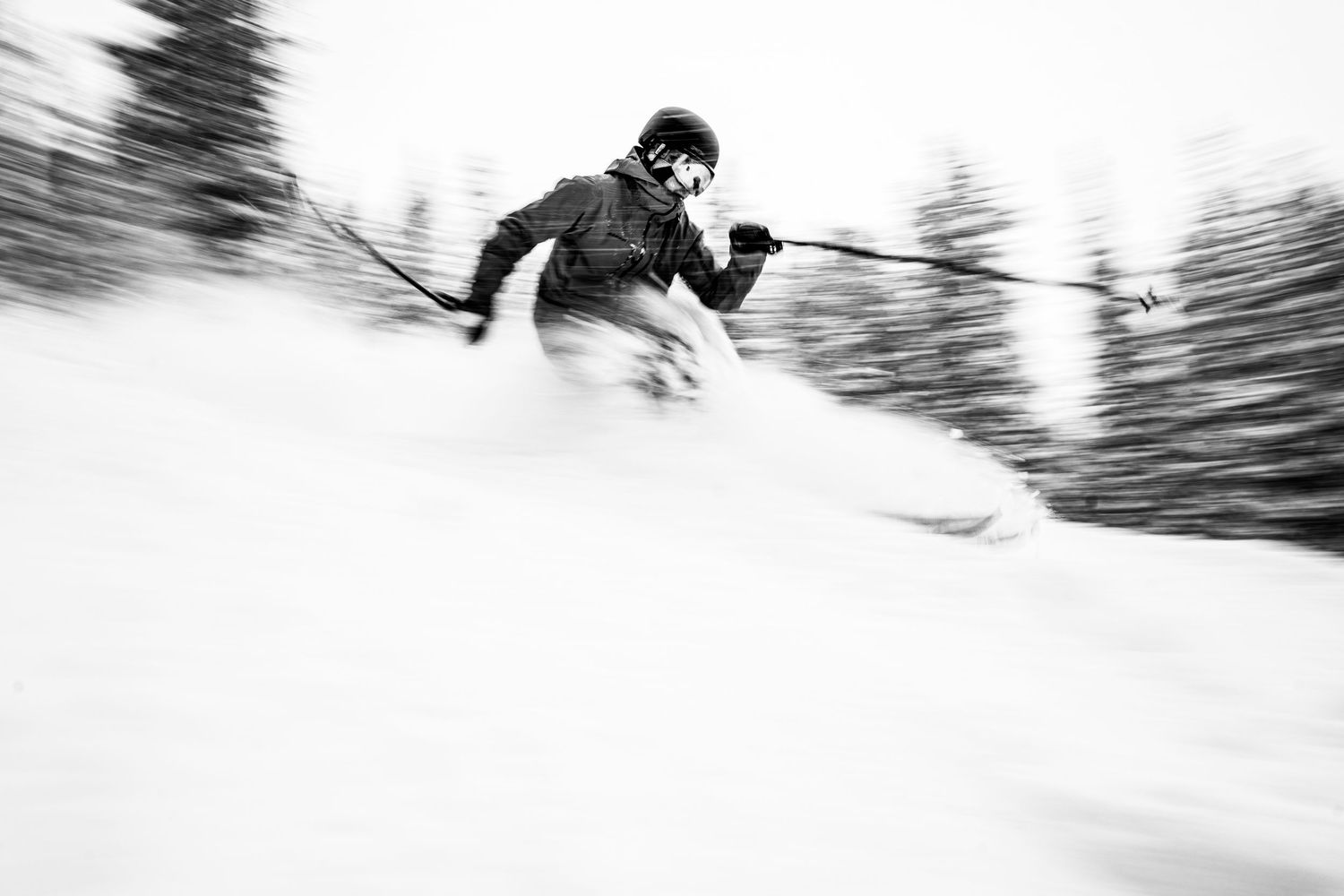 Dynamic black and white photo of skier racing downhill through blurred winter landscape.