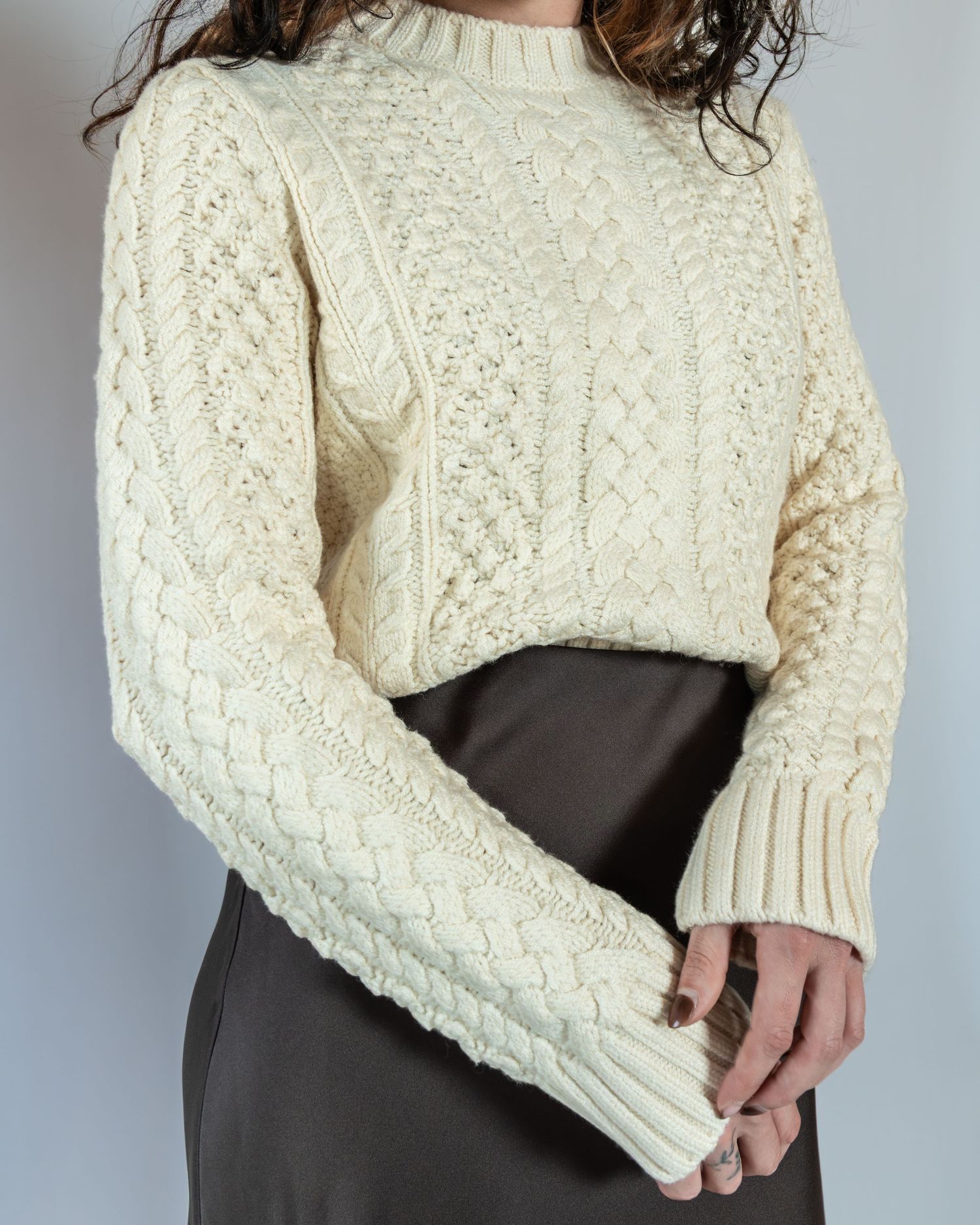 A cream cable knit sweater styled with a dark pencil skirt in a series of close-up detail shots.