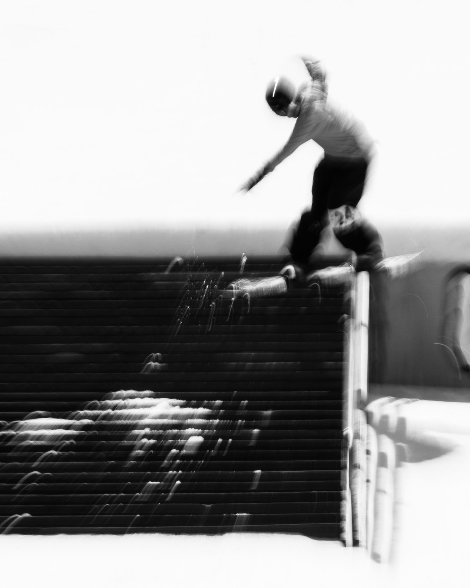 Black and white photo of a skateboarder performing a trick on a ledge, captured with motion blur.