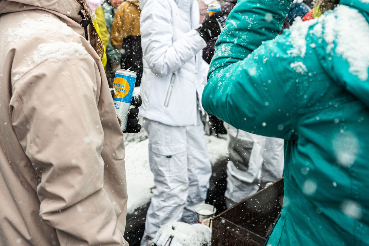 Winter sports enthusiasts gather in snowy conditions wearing protective gear and winter clothing.