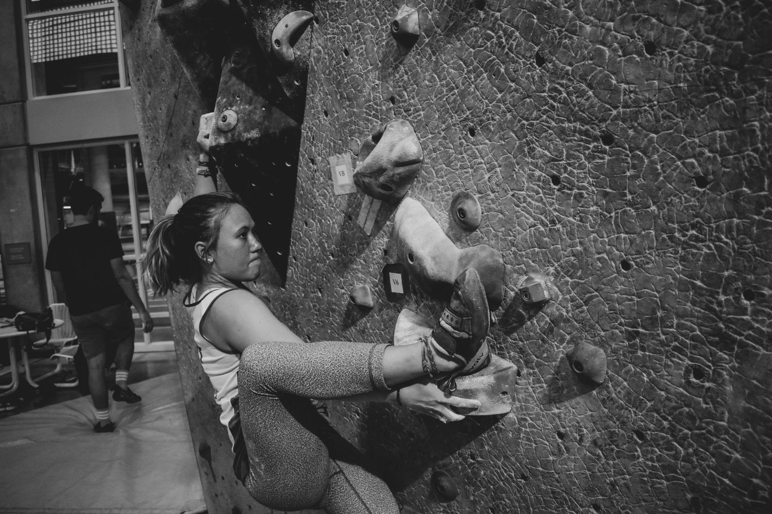 Climber executing a technical move on an indoor climbing wall.