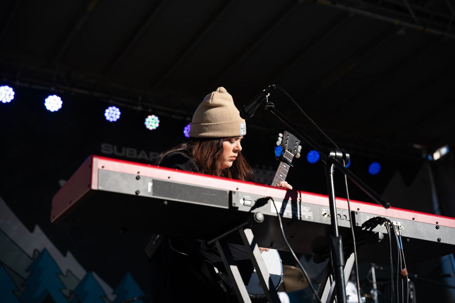 Musician performing at keyboard on dimly lit stage.