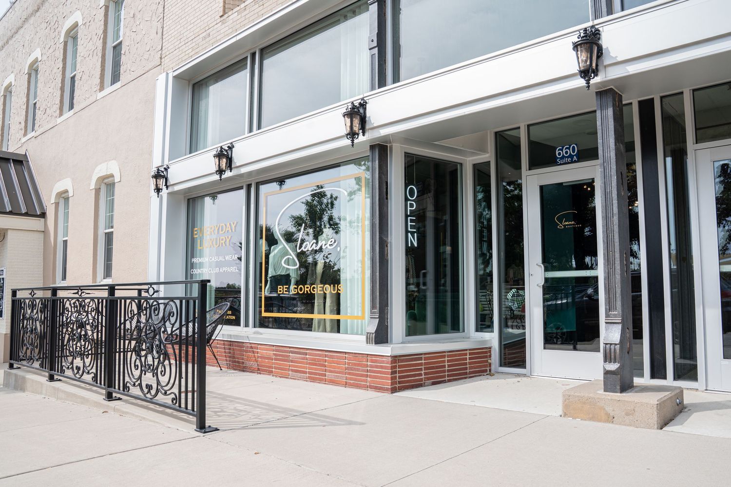 Exterior storefront with large windows, black iron railings, brick facade, and open sign at number 660.