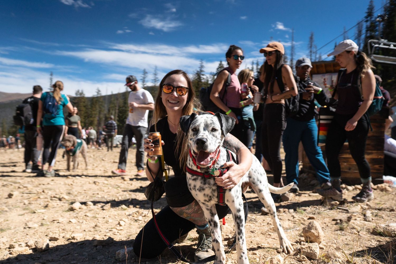 Dalmatian dog with group of outdoor enthusiasts on sunny mountain trail.