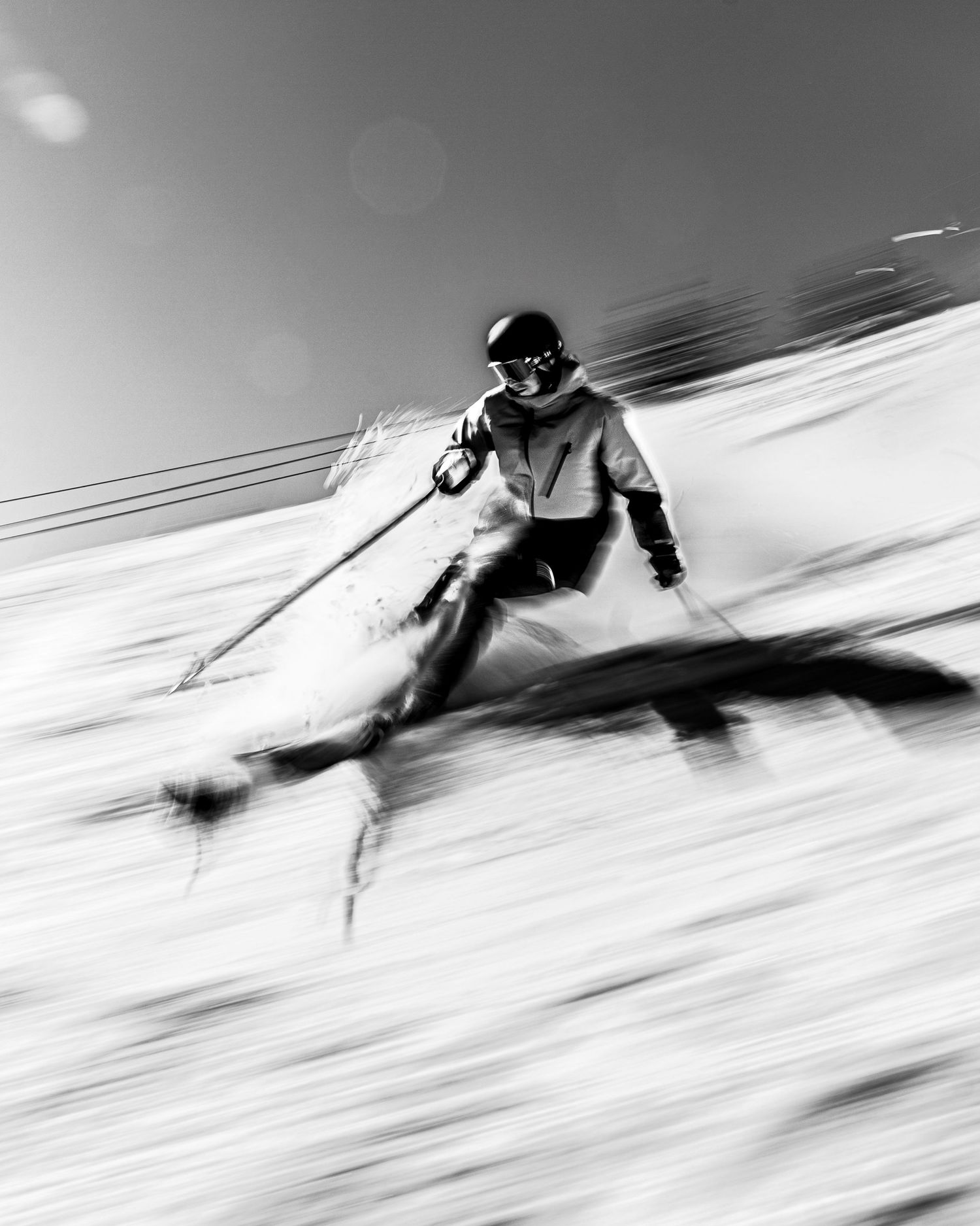 Dynamic black and white action shot of a skier carving through fresh powder at high speed.