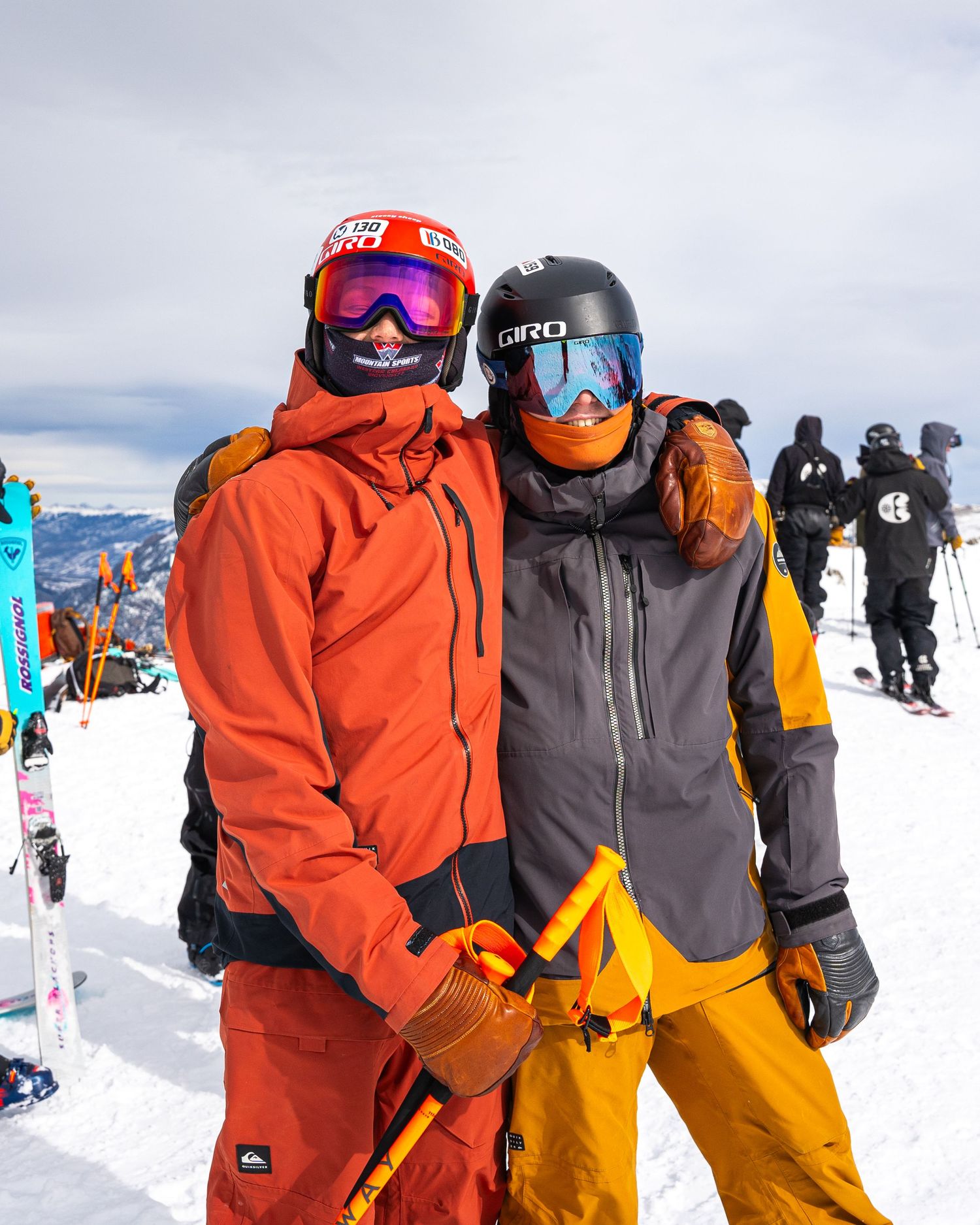 Two skiers in bright winter gear pose together on snowy mountain slope.