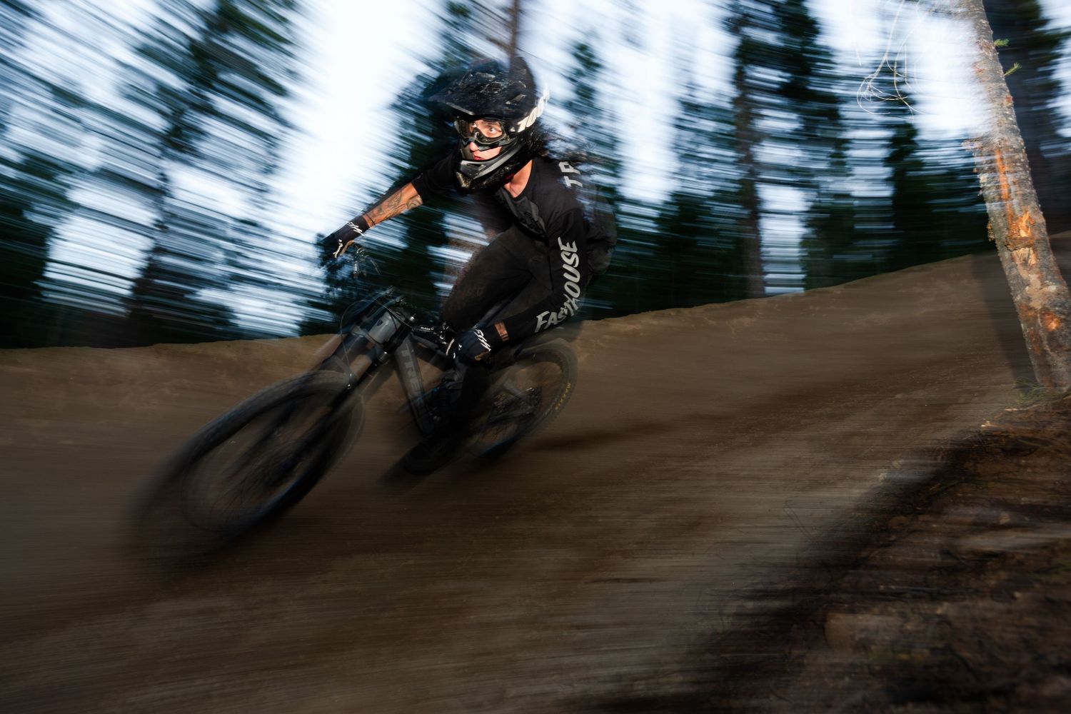 Mountain biker rides at high speed through a forest trail with motion blur effect.