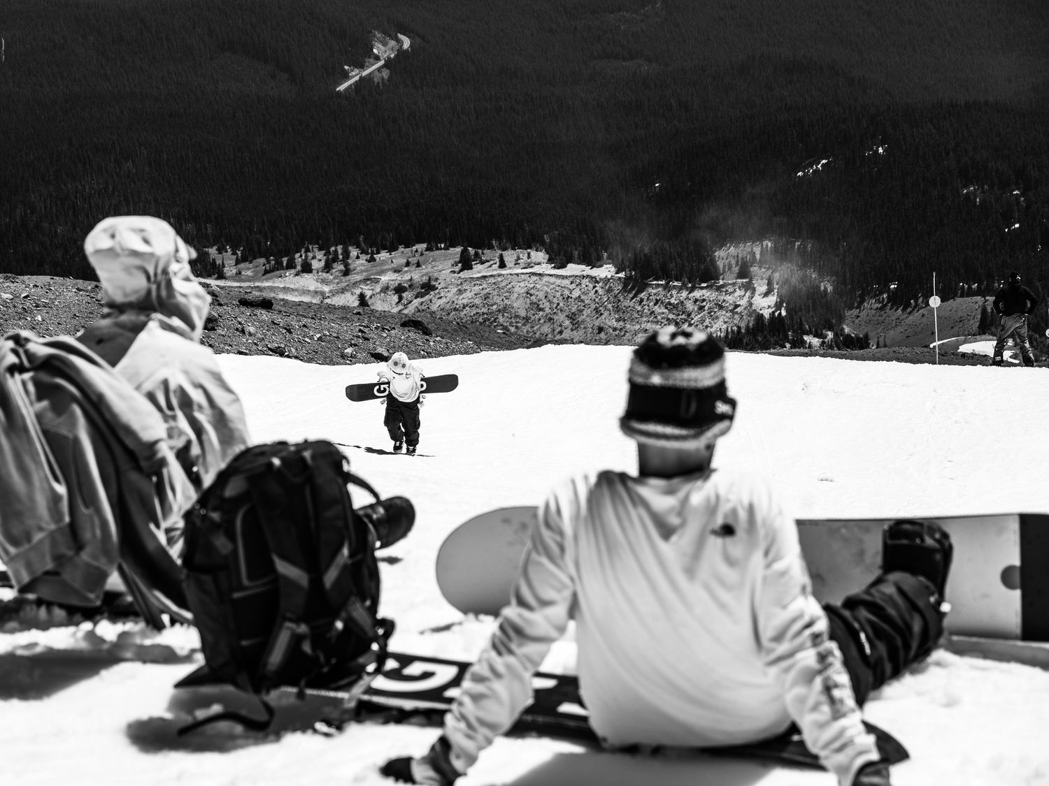 Vintage black and white photo of skiers resting on snowy slope.