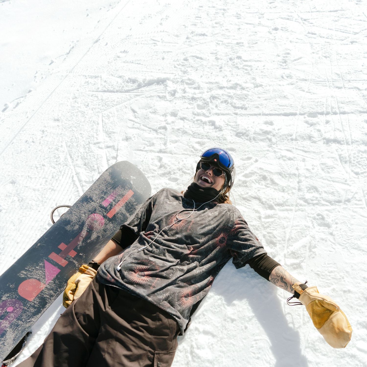 Snowboarder resting on snowy slope with board visible.