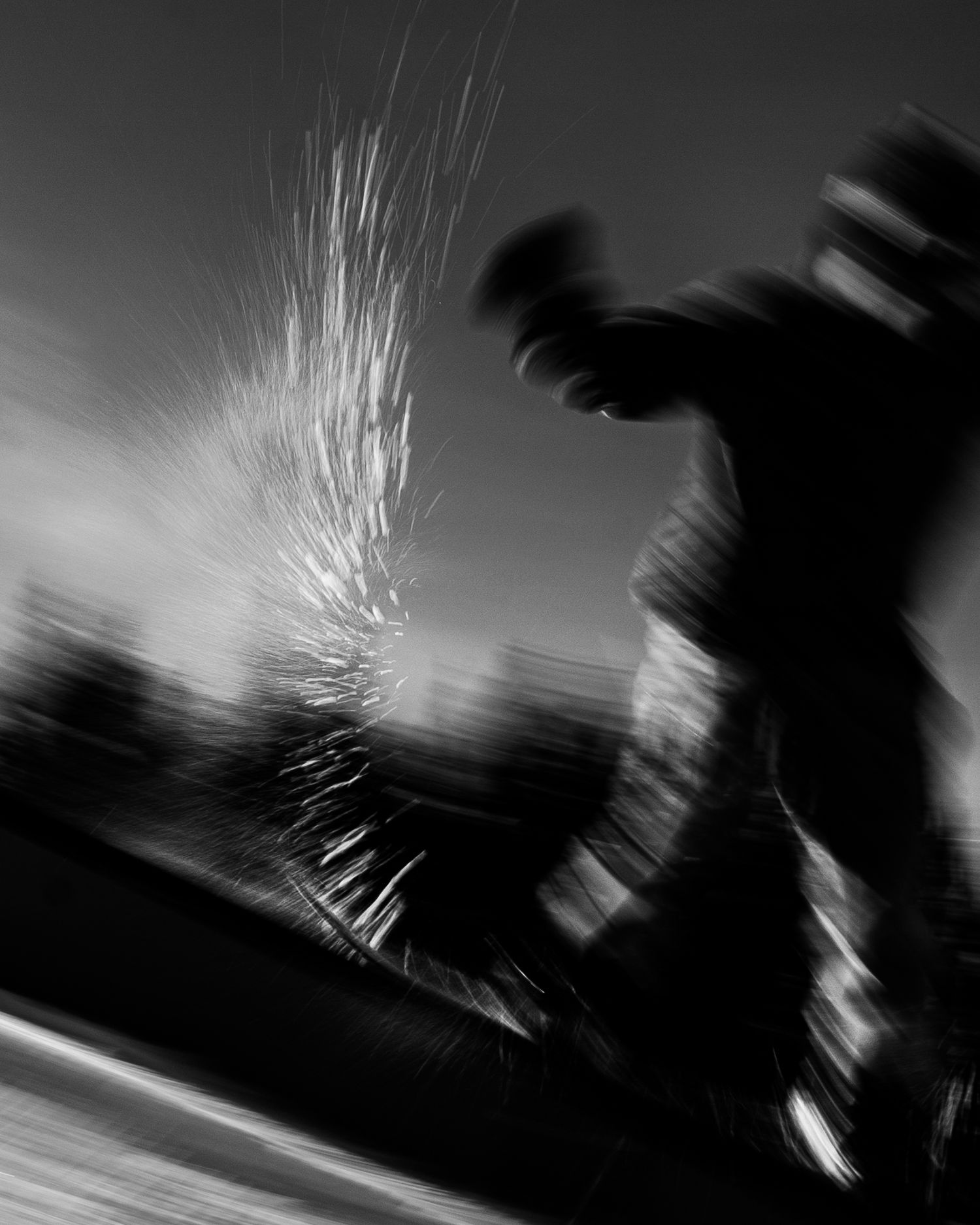 Dynamic black and white action shot of snowboarder creating spray of snow.
