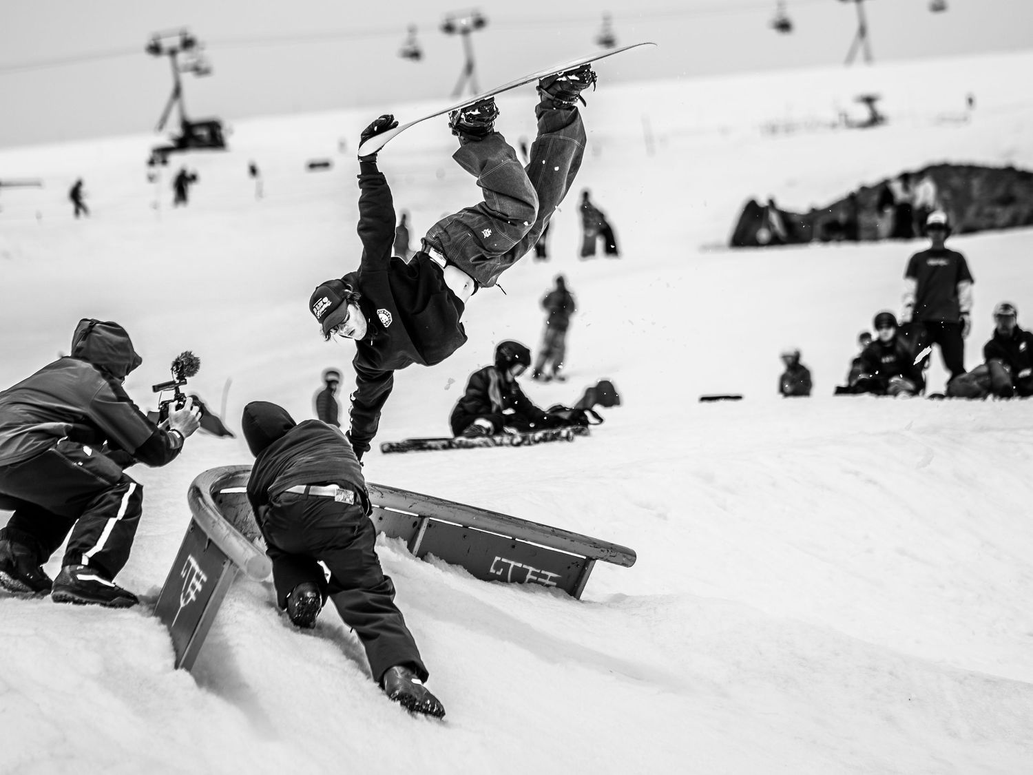 Dynamic black and white shot of snowboarder performing inverted aerial trick.