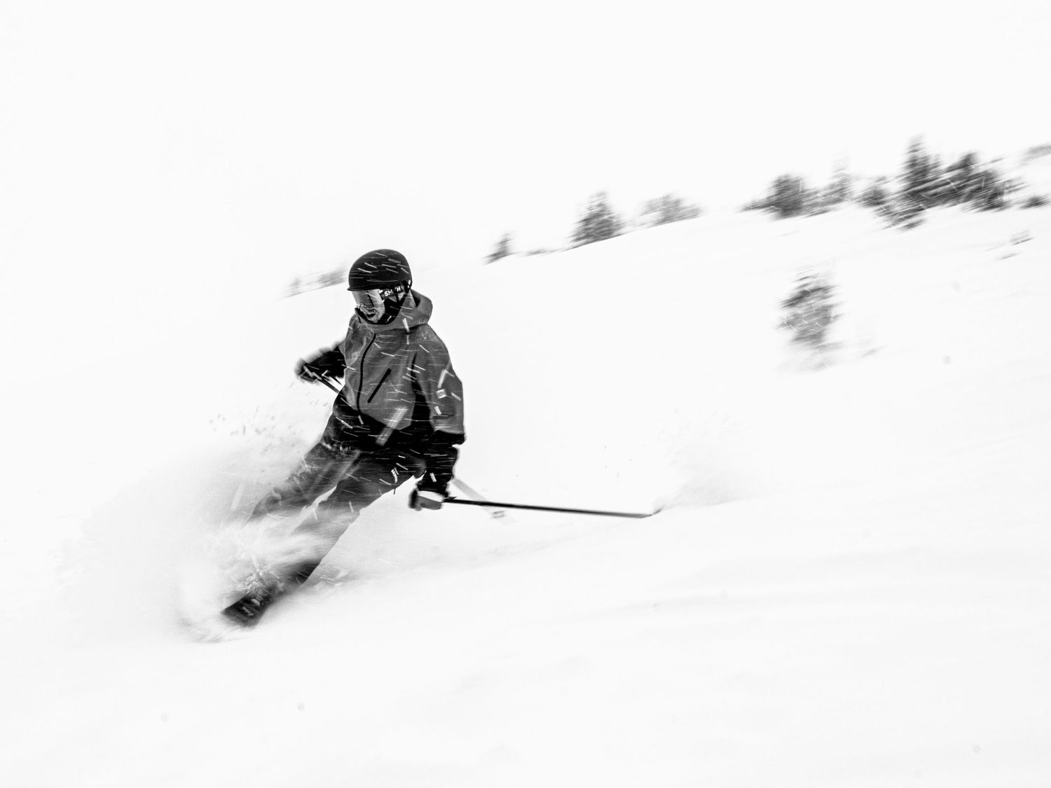 Dynamic black and white shot of skier making graceful turn in deep powder snow.