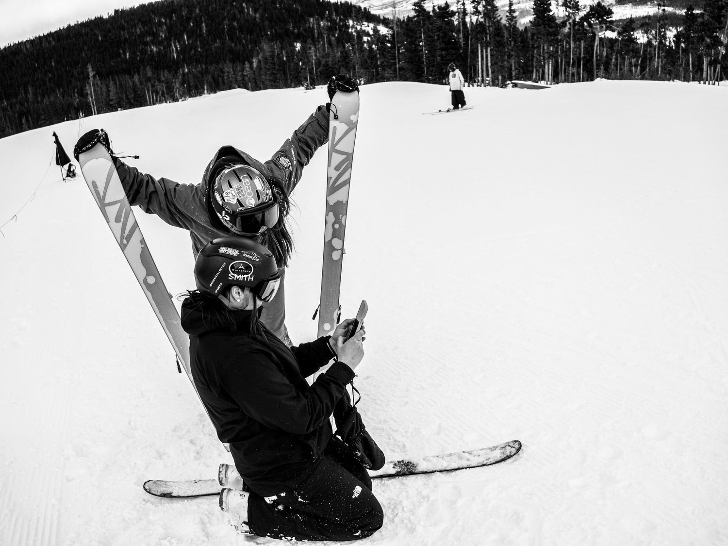 Two skiers celebrating on snowy slopes in black and white photography.