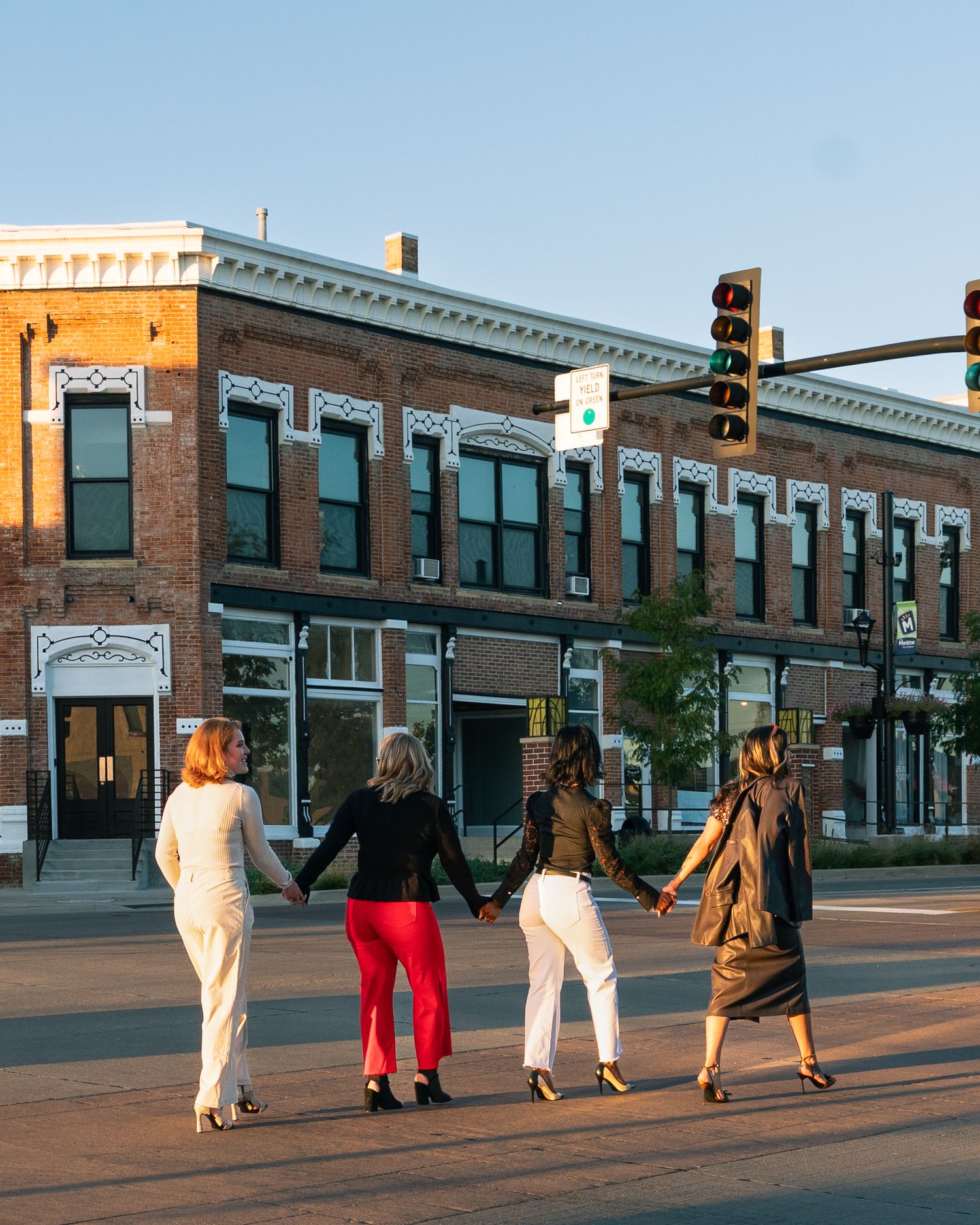 Group walking down a brick-paved street at sunset next to historic commercial buildings.