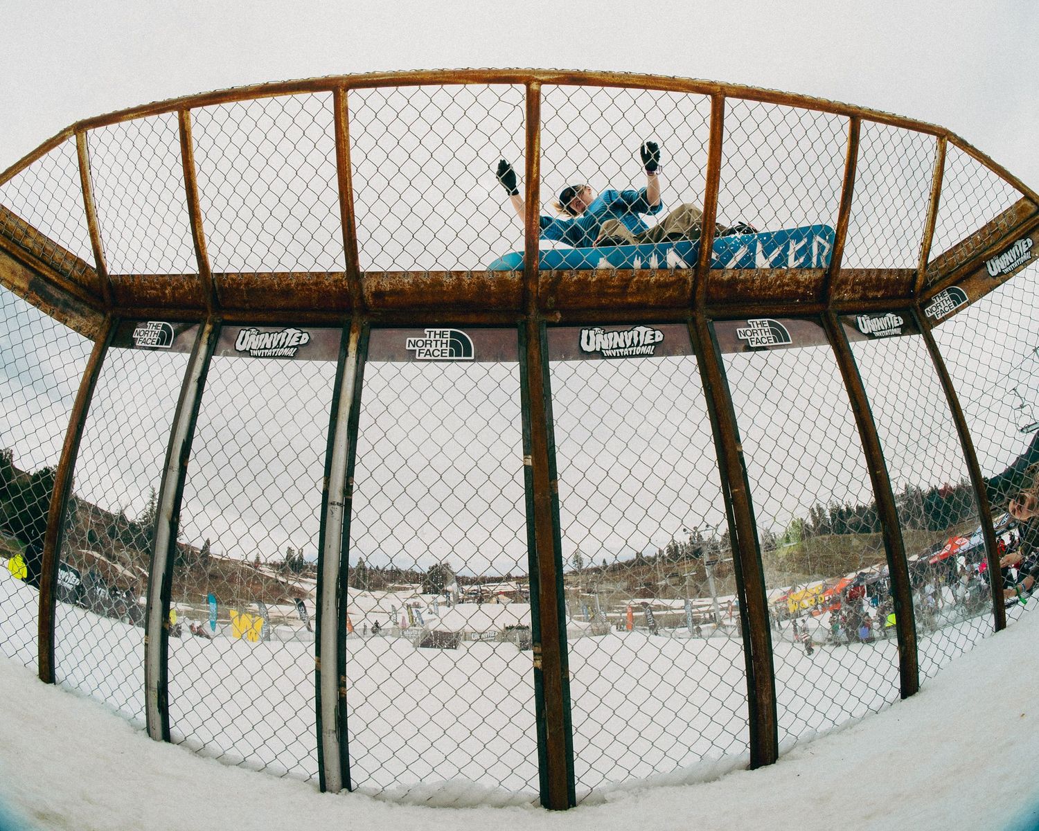 Snowboarder captured through a fisheye lens performing a trick in a halfpipe at Woodward.